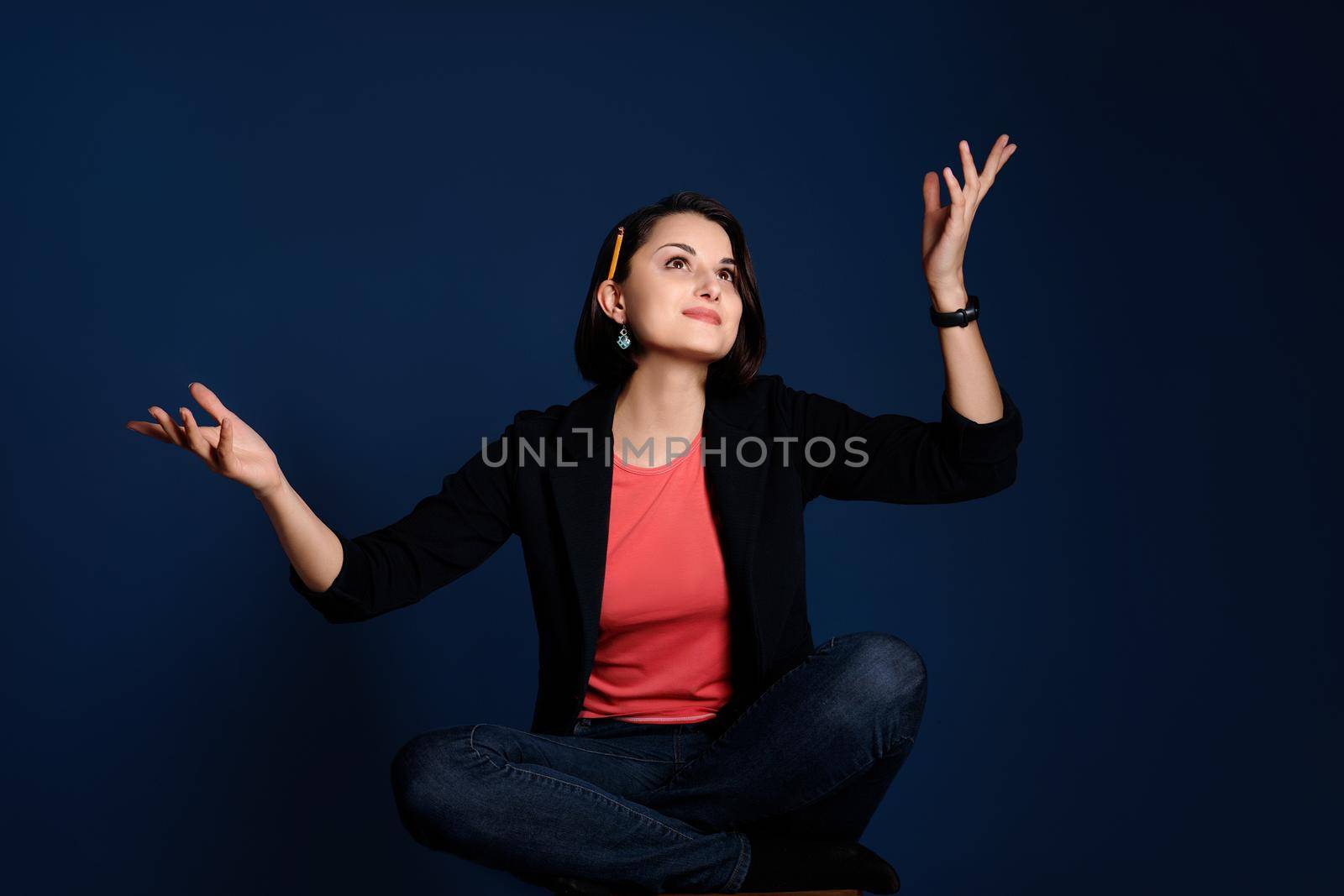 Portrait of a young woman blogger or copywriter with a pencil behind her ear looking for inspiration for new ideas on blue background