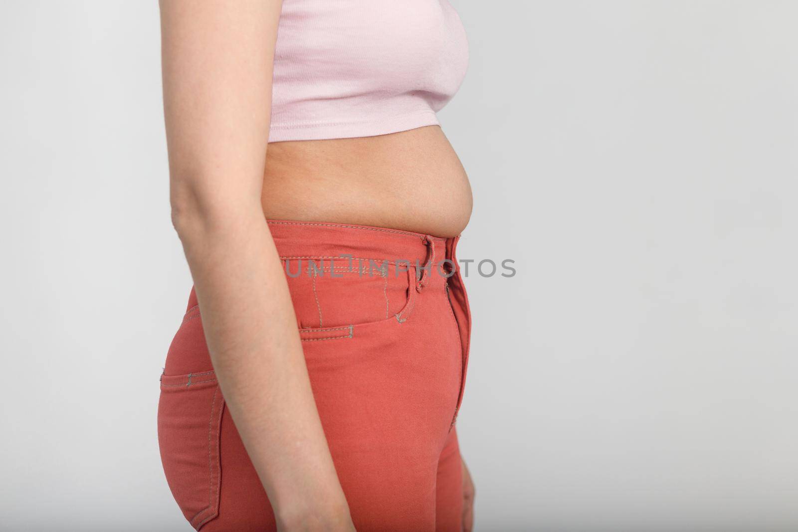 Side view of belly of a slightly overweight young woman. Diet, overweight, obesity concept by Rom4ek