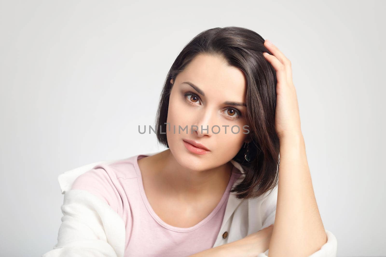 Young multiethnic brunette woman studio portrait. Bright white colors. Beautiful woman with simple makeup looking at the camera. High-key headshot