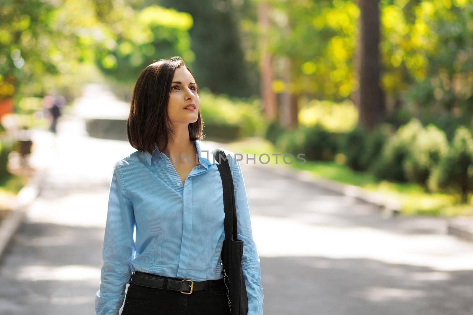 Beautiful brunette woman walking in the park on a summer sunny day.