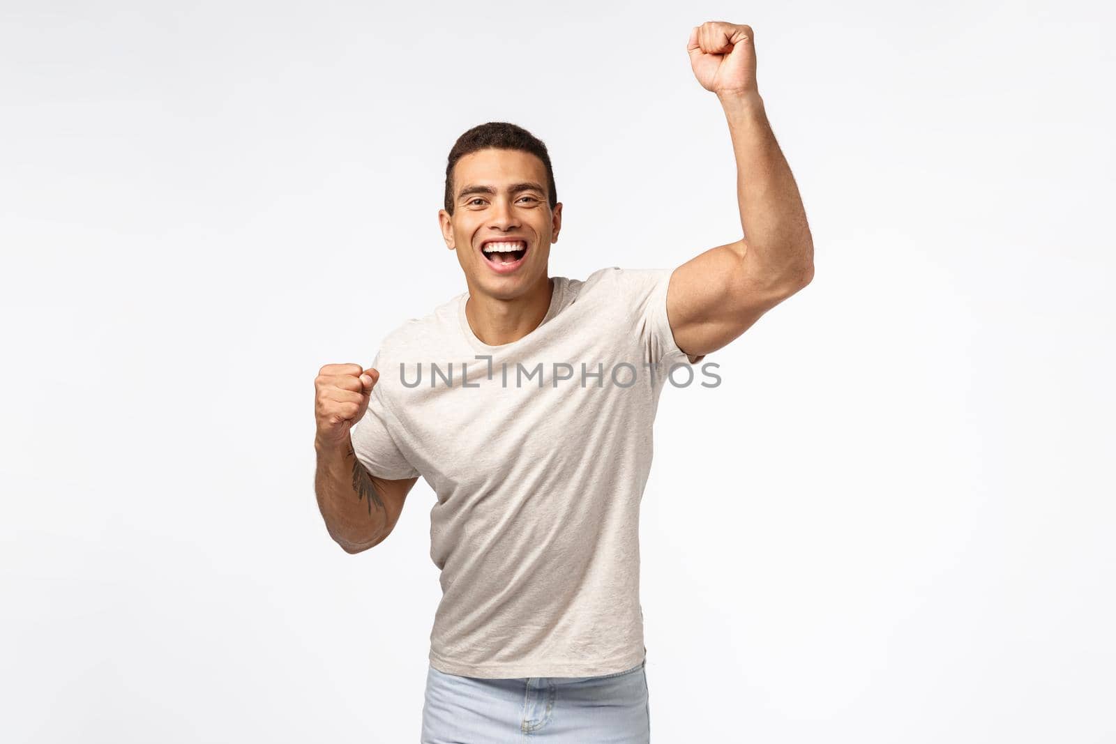 Man lift hand up in hooray motion, cheering for favorite sports team. Handsome young strong guy fist pump and smiling, encourage friend score goal, rooting for someone, placed bet white background.