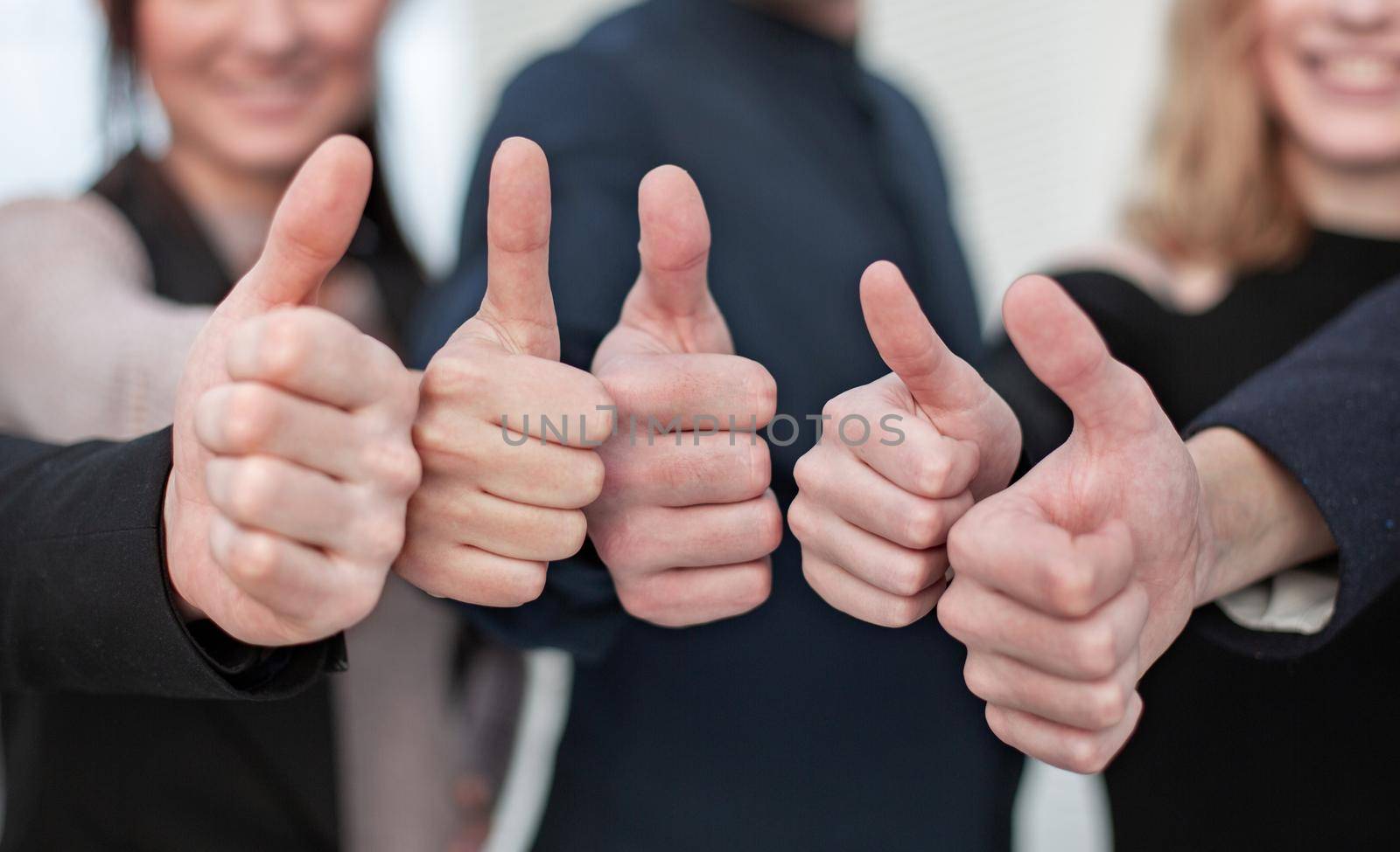 Close-up of group of business people raising their arms up and showing thumbs up