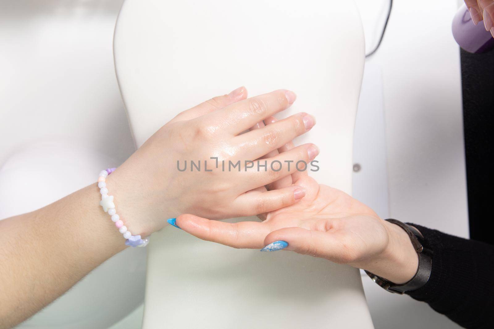 Manicurist sprays antiseptic on the nails before treating old acrylic nails. Treatment of nails with a disinfectant before manicure. Applying a disinfectant to women
