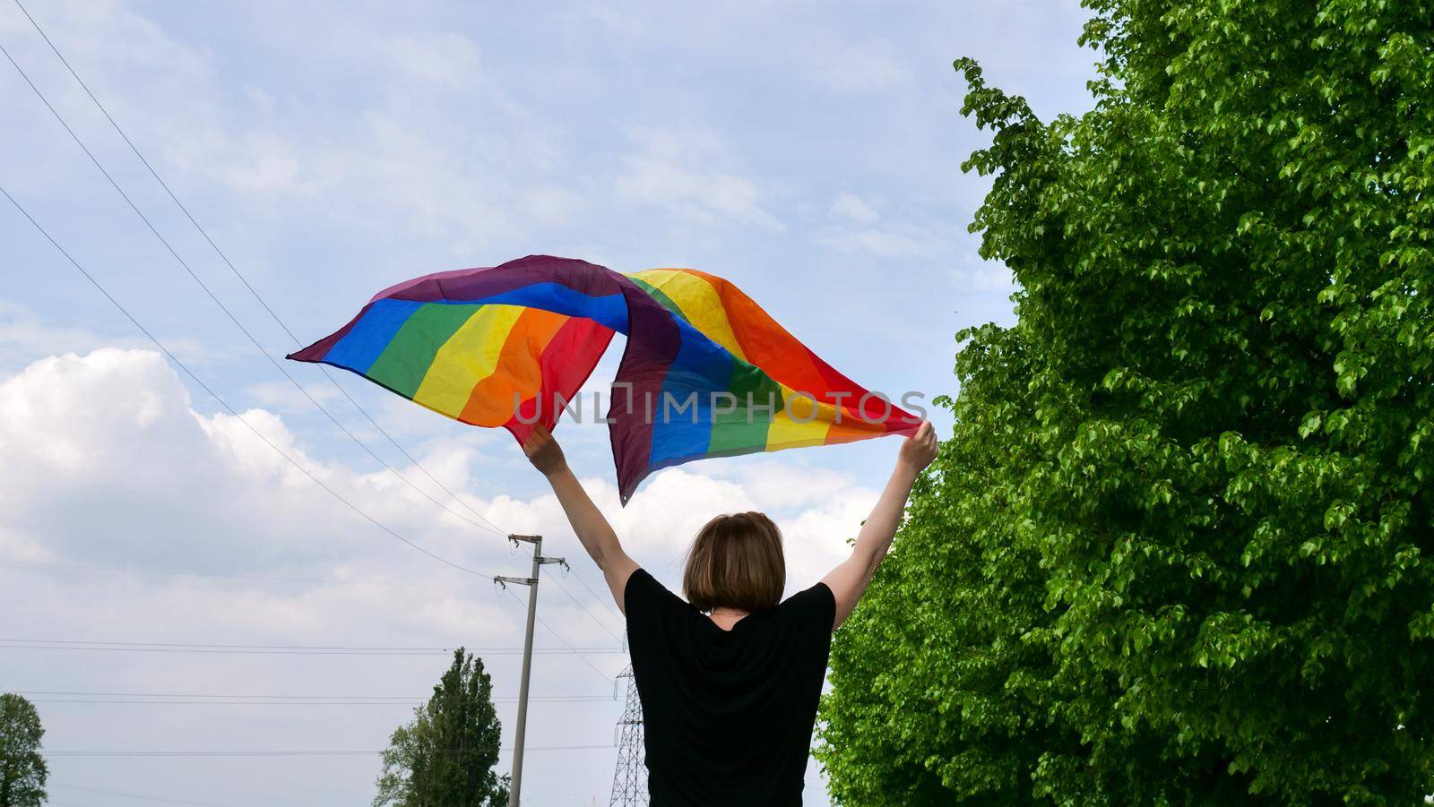 Woman holding rainbow flag on sky background by OksanaFedorchuk