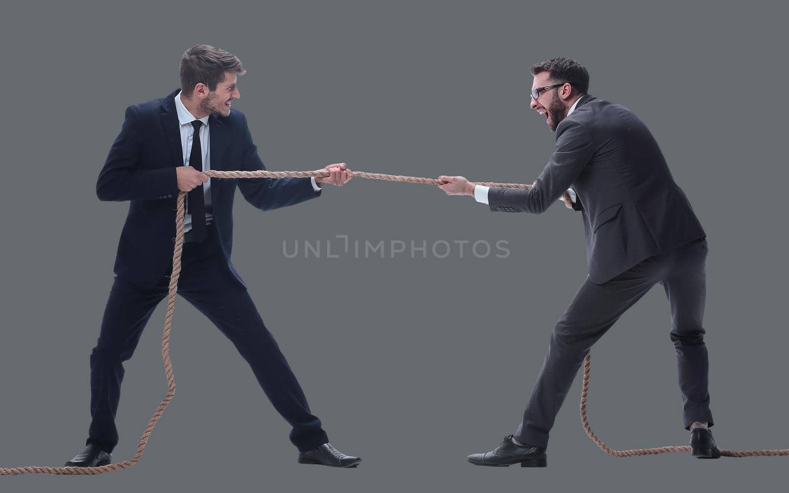 full length . two smiling businessmen pulling the rope. isolated on white background.