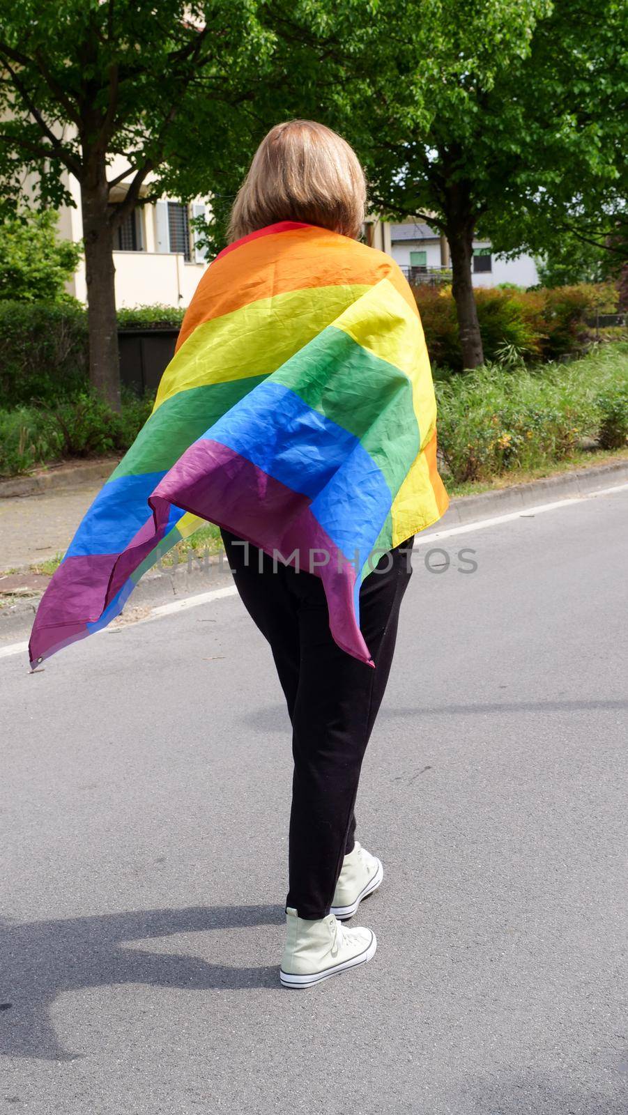 Bisexual, lesbian, woman, transgender stands with LGBT flag against blue sky with clouds on a sunny day and Celebrate Bisexuality Day or National Coming Out Day