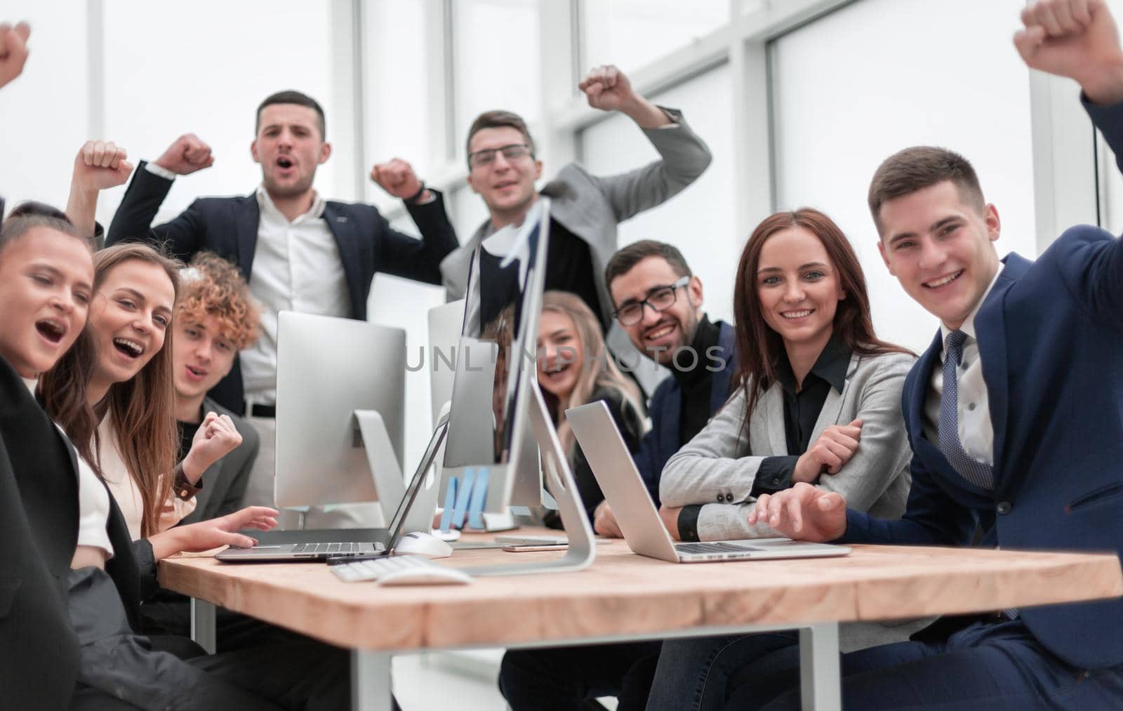 group of happy office employees sitting at a table. by asdf