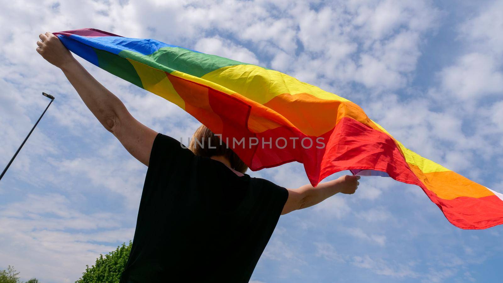 LGBT pride, rainbow peace flag against blue sky with clouds on a sunny day and Celebrate Bisexuality Day or National Coming Out Day