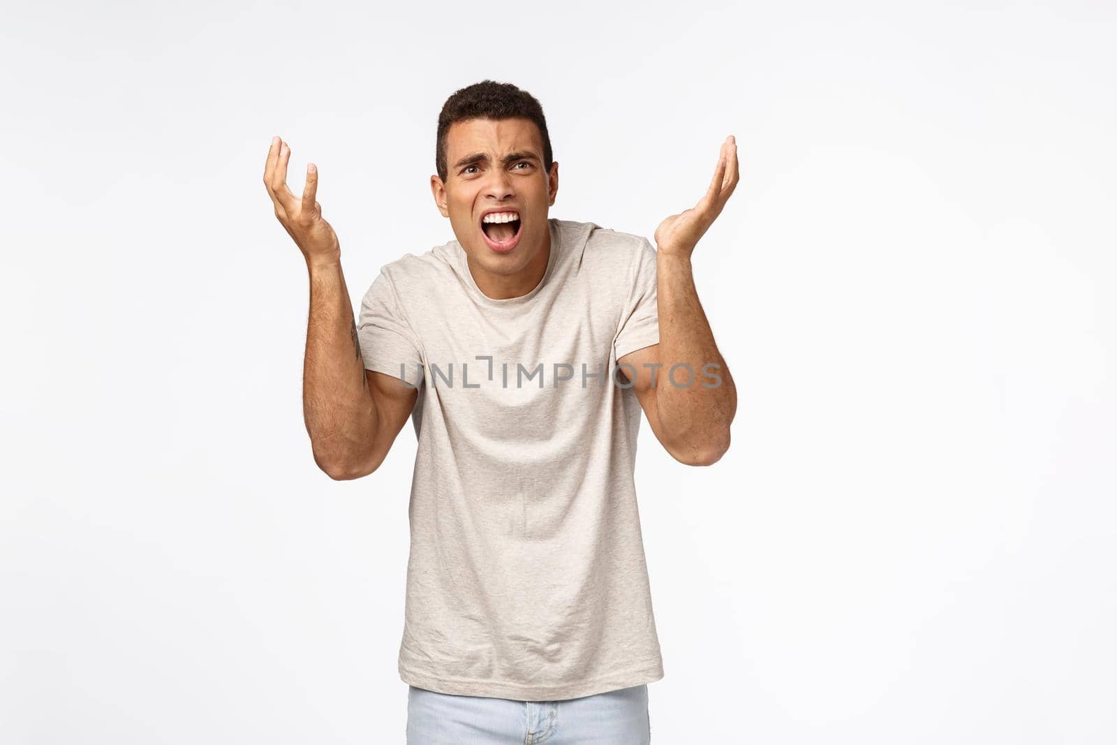 Disappointed and freak-out, bothered handsome man in t-shirt, raising hands up frustrated and displeased, arguing, complaining over unfair failure, losing competition, standing upset white background.