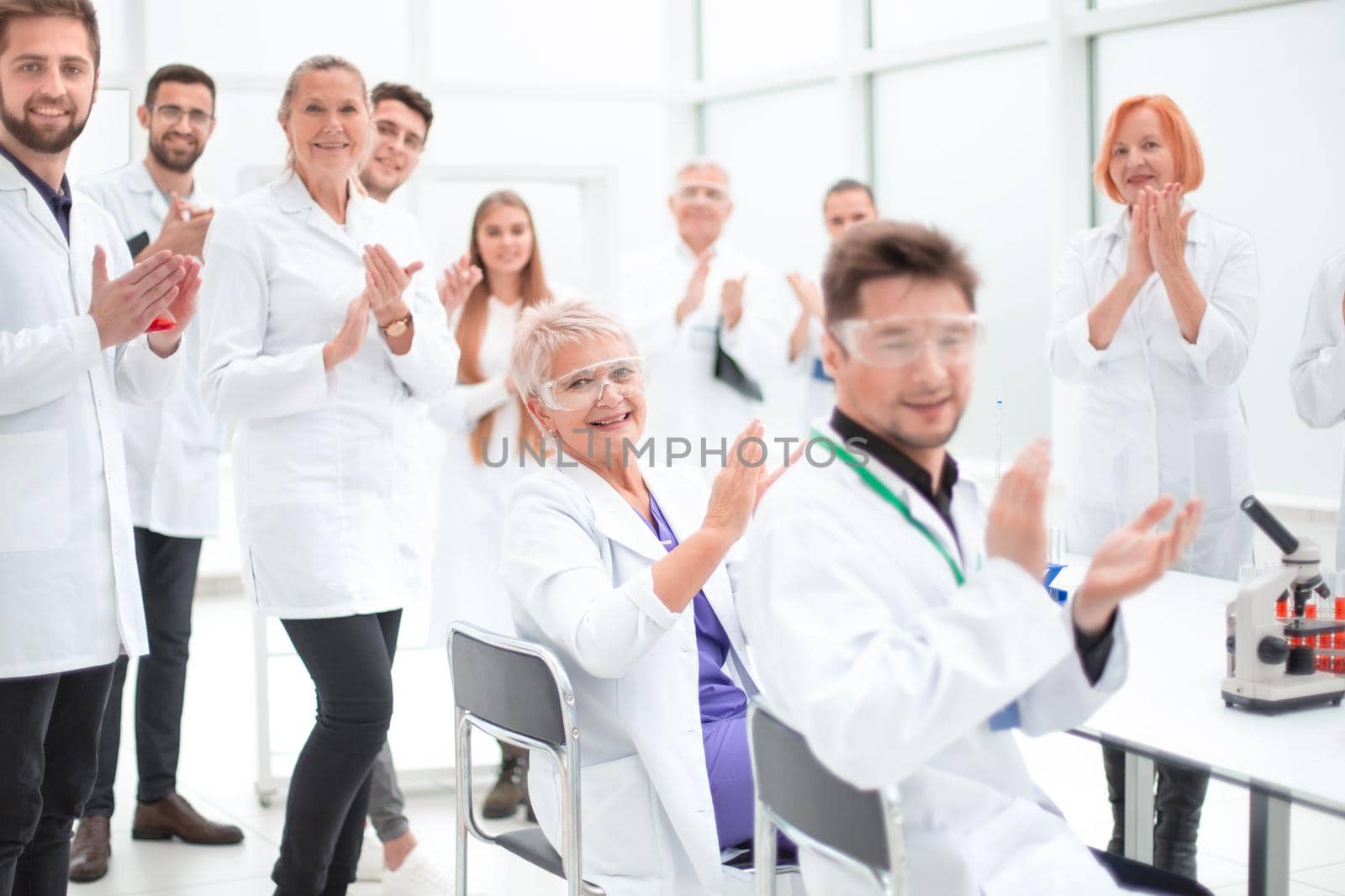 group of young scientists congratulating their colleague with applause . concept of success