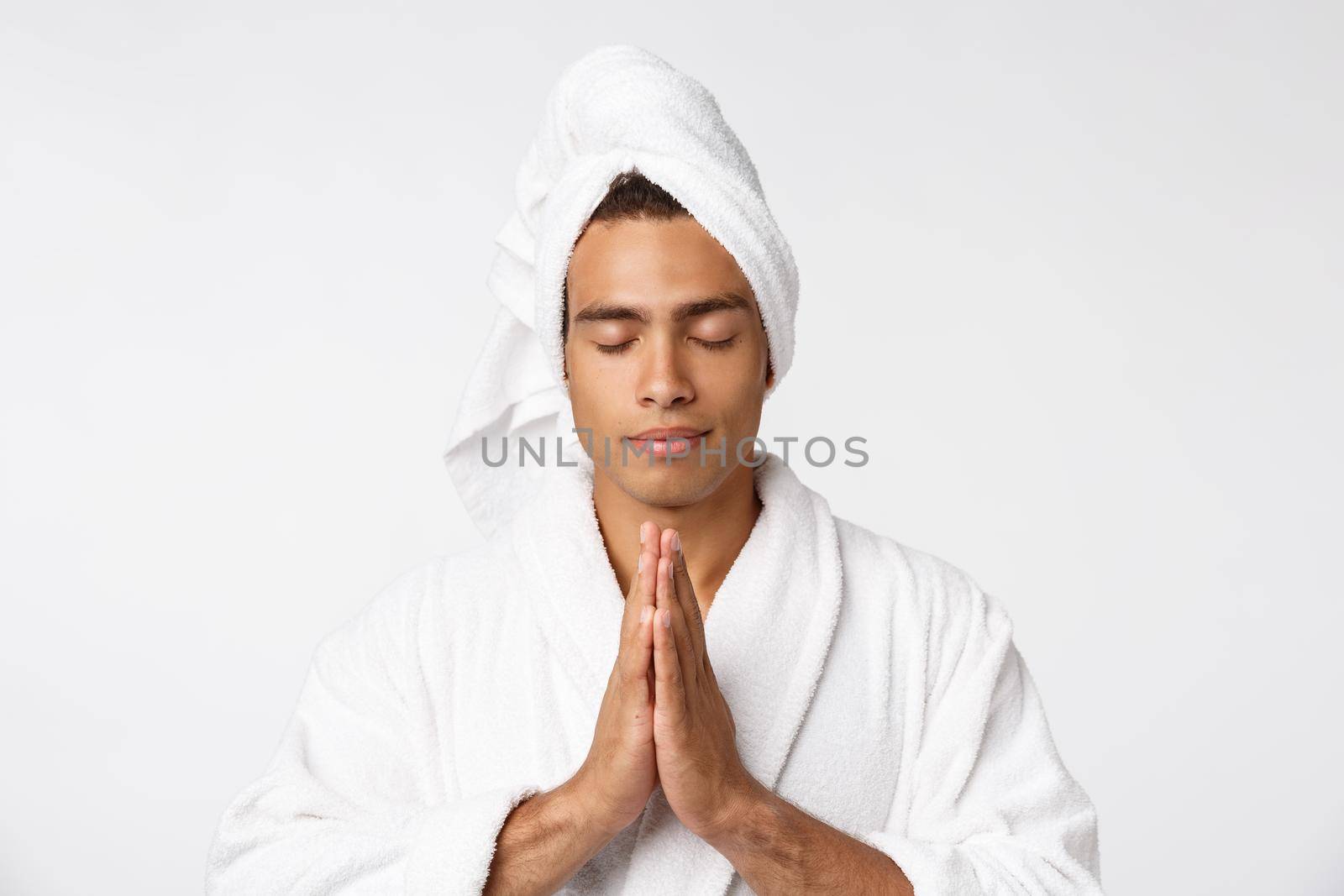 Calm spiritual handsome African guy praying. Serious peaceful young man with joining hands meditating. Belief concept.