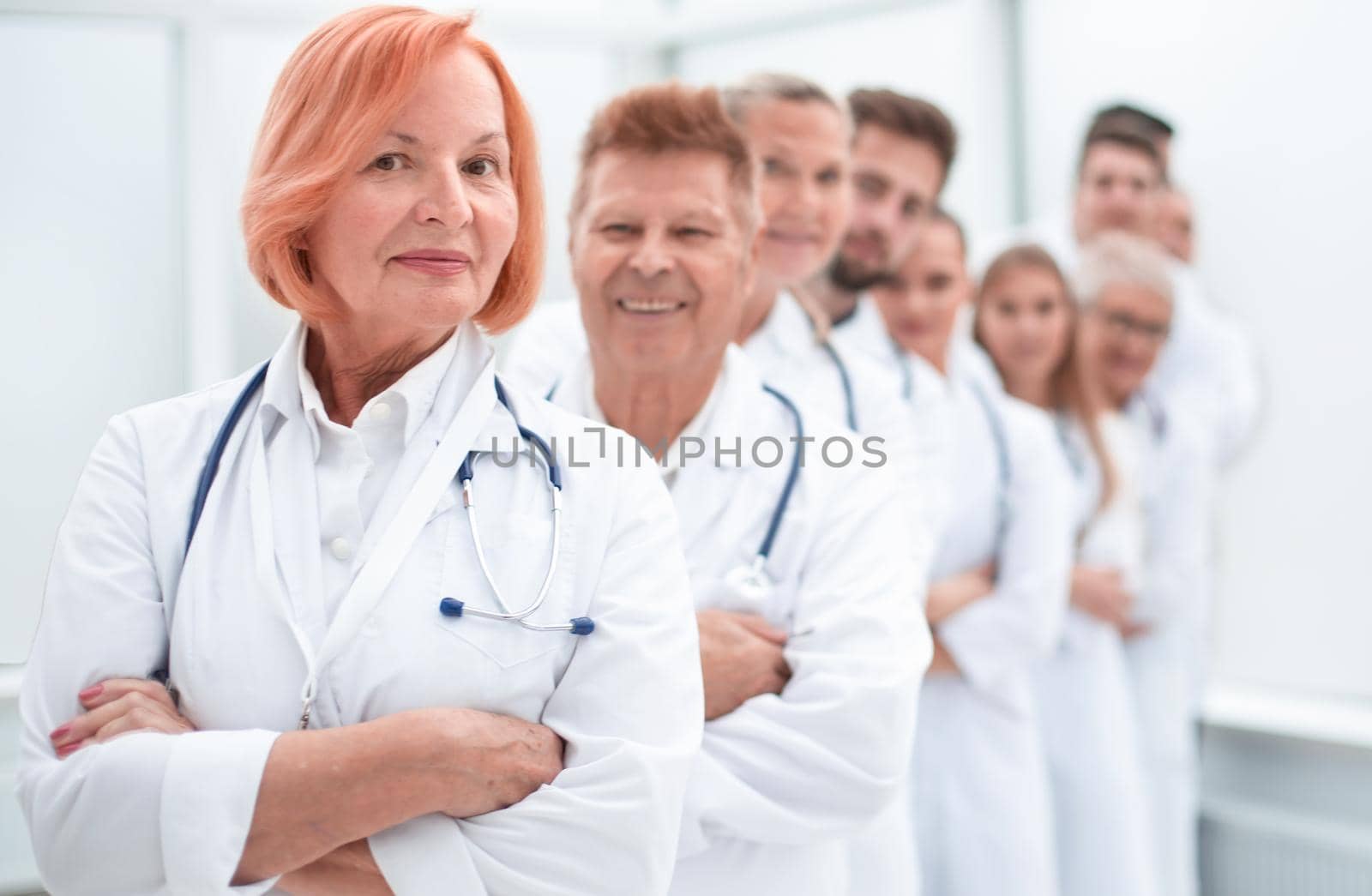 close up. Mature female doctor standing in front of her colleagues. by asdf