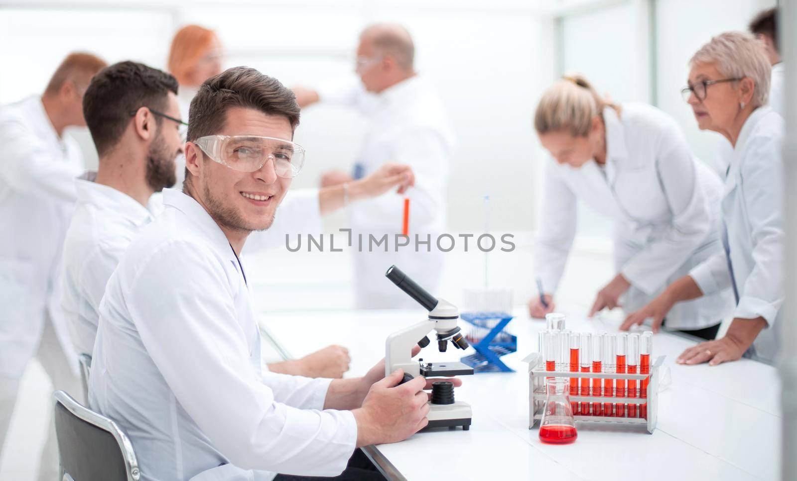 young scientist and his colleagues work in the laboratory. by asdf