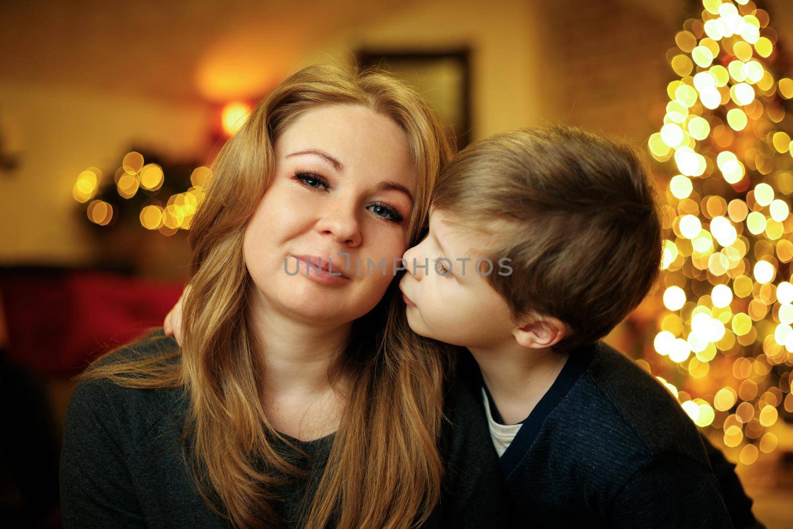 Boy 5-7 years old kisses his mother in a festive New Year's interior by Rom4ek