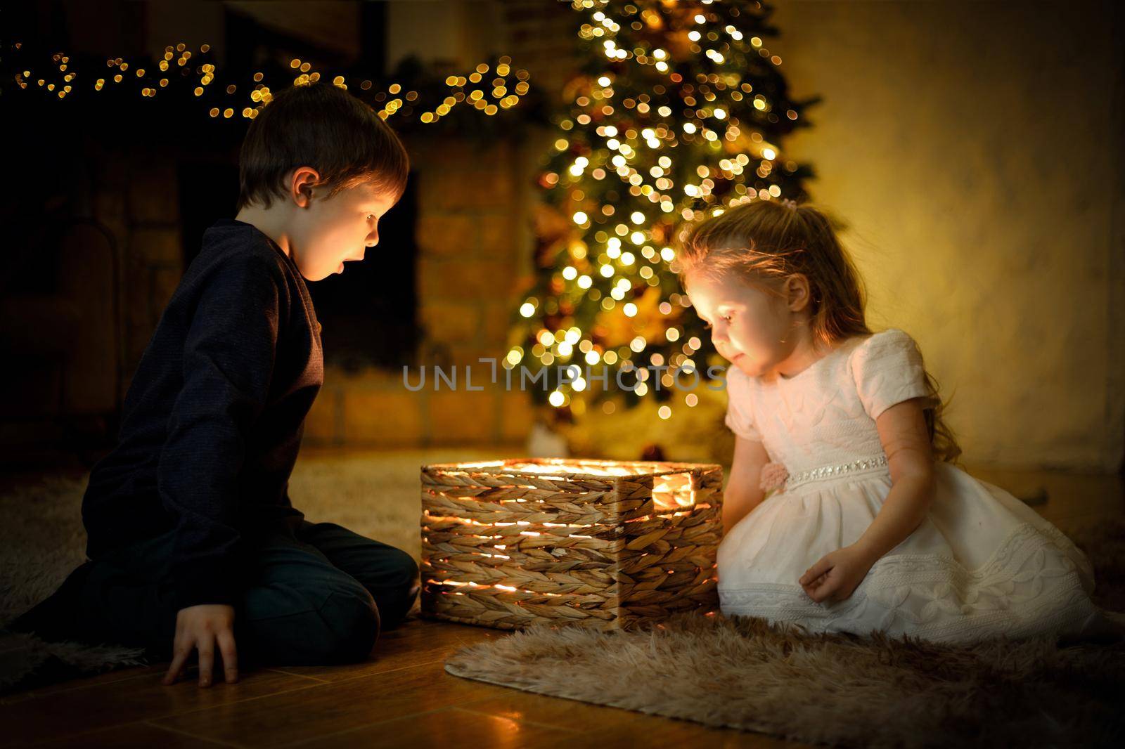 Children opened a magical New Year's gift in a Christmas interior with a Christmas tree and garlands. Selective soft focus, film grain effect