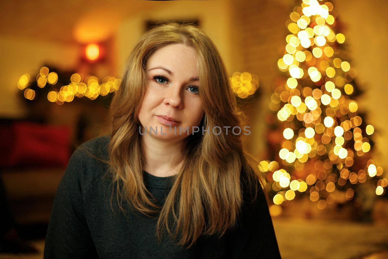 Portrait of a 30 year old beautiful redhead woman in a festive new year interior with christmas tree. Selective soft focus, film grain effect