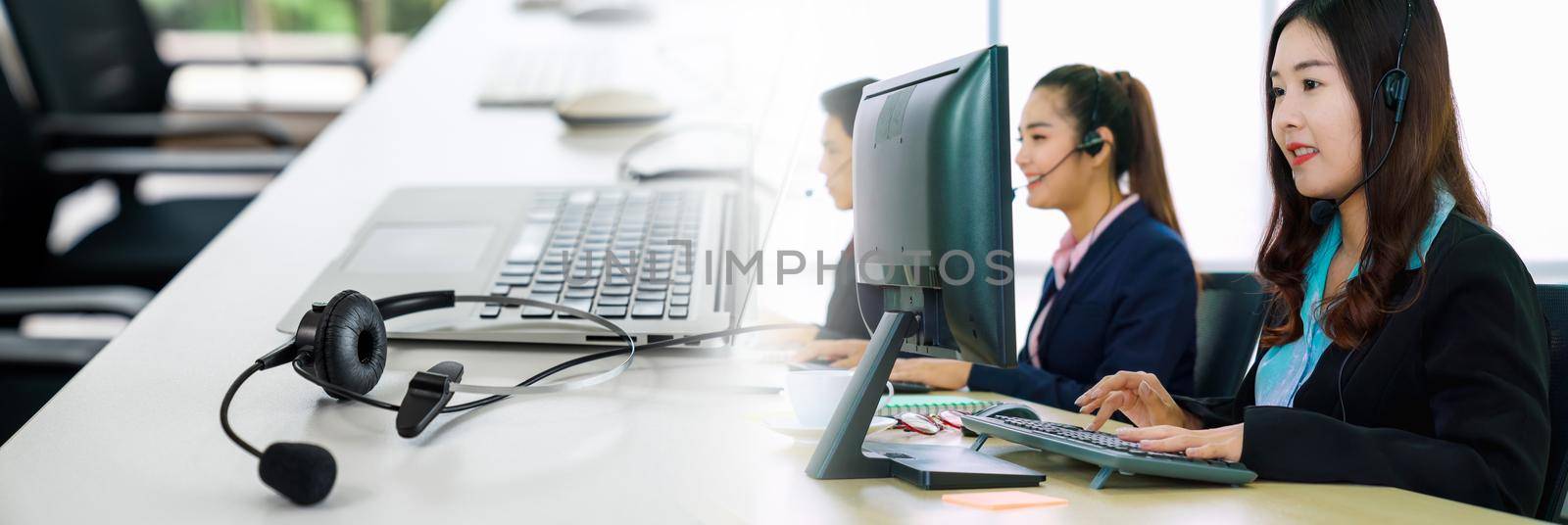 Business people wearing headset working in office in widen view to support remote customer or colleague. Call center, telemarketing, customer support agent provide service on telephone video call.