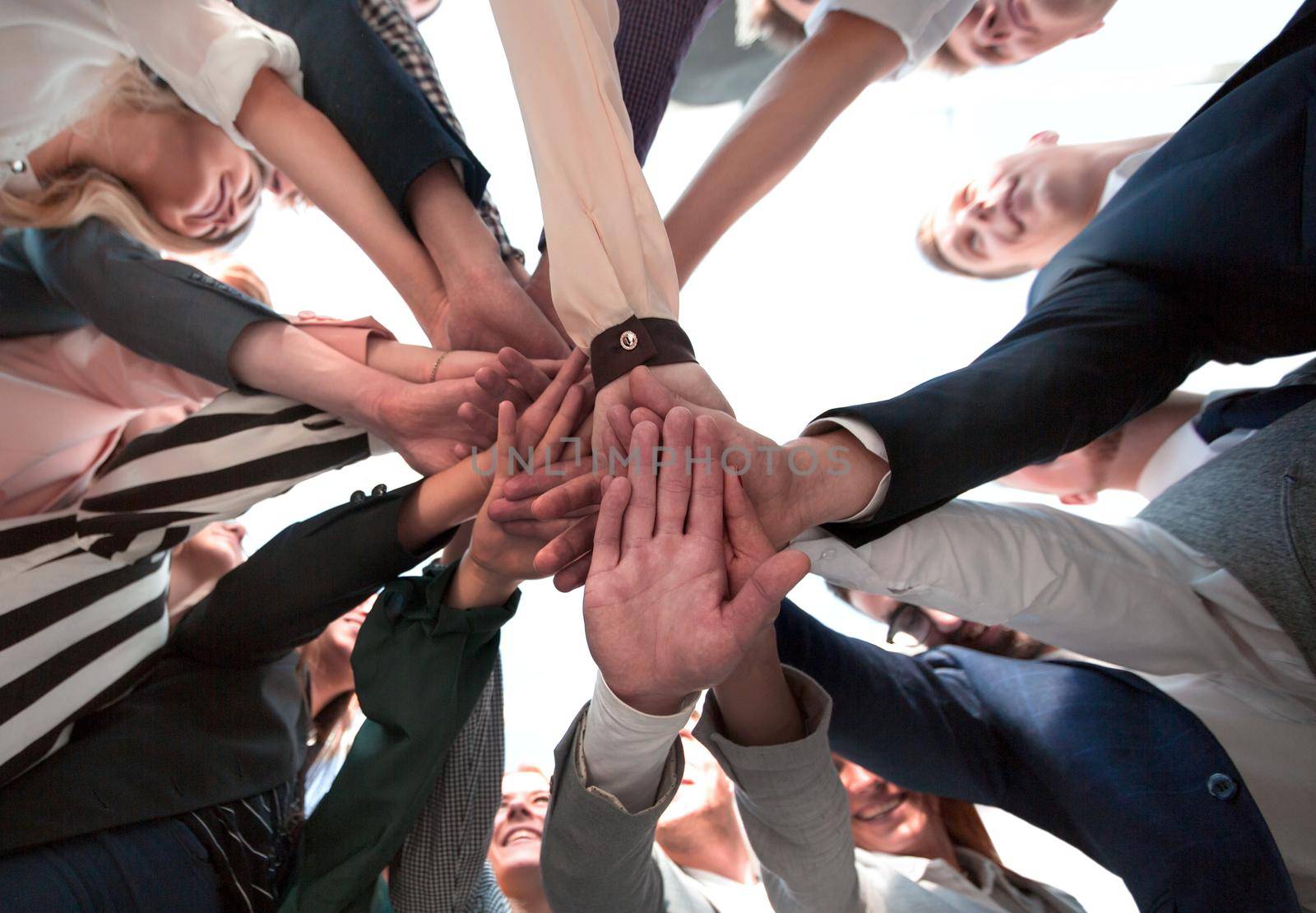 group of diverse young people folding their hands in a circle by asdf