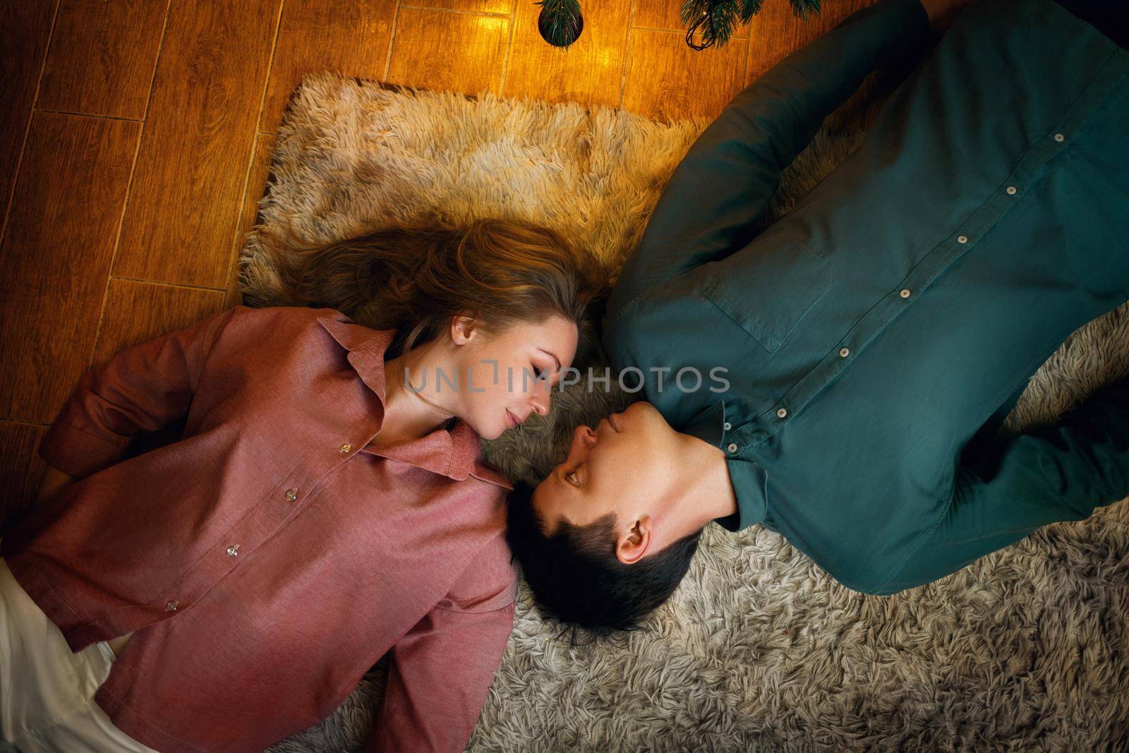 Beautiful middle aged caucasian couple lies on the cozy carpet. top view. film grain effect