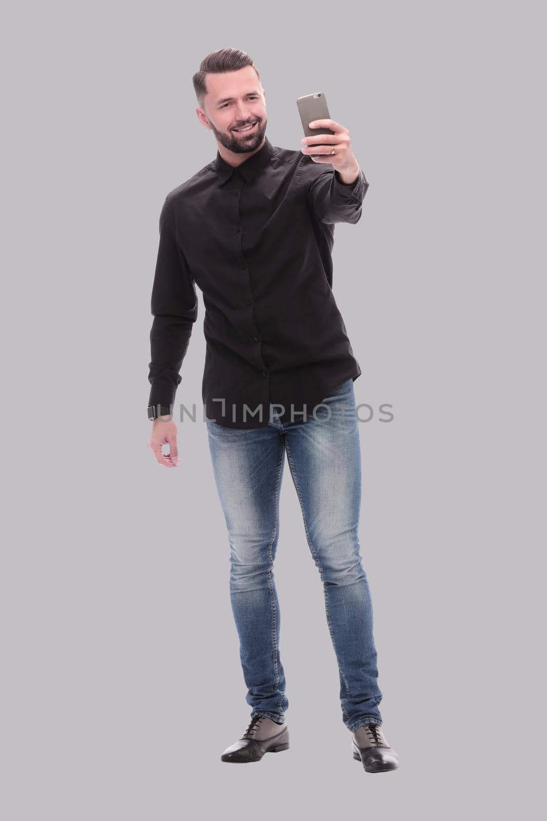 in full growth. a young man in jeans taking selfies . isolated on white background