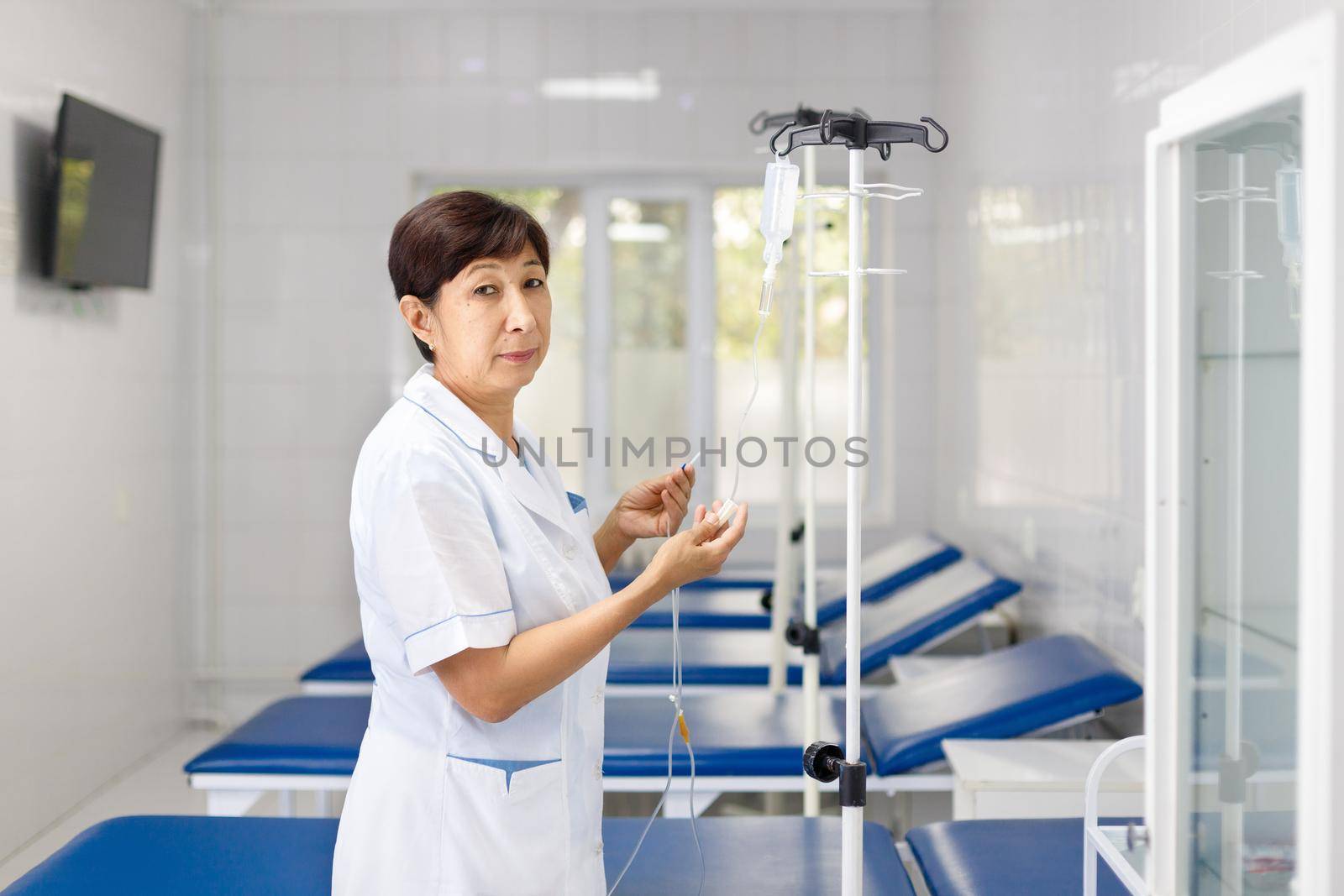 Central Asian senior nurse ready to put saline drip.