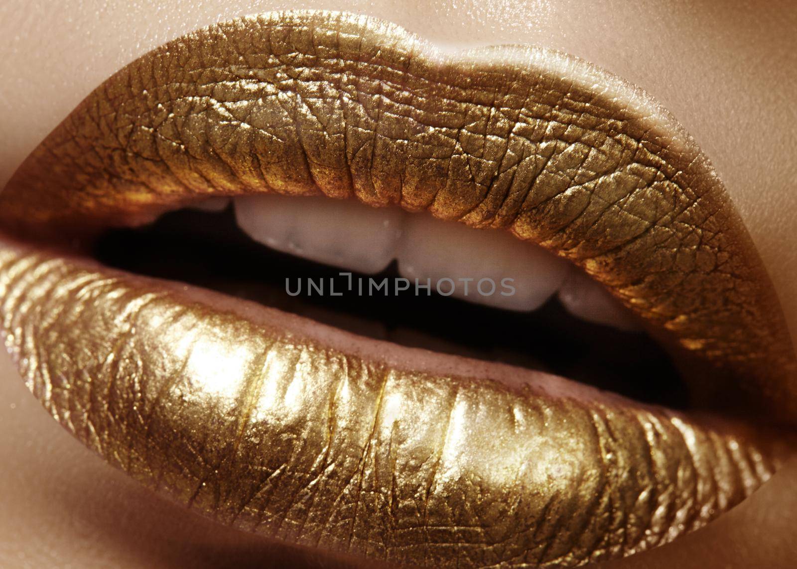 Beautiful closeup with female plump lips with gold color makeup. Fashion celebrate make-up, glitter cosmetic. Shine christmas style. Metalic makeup