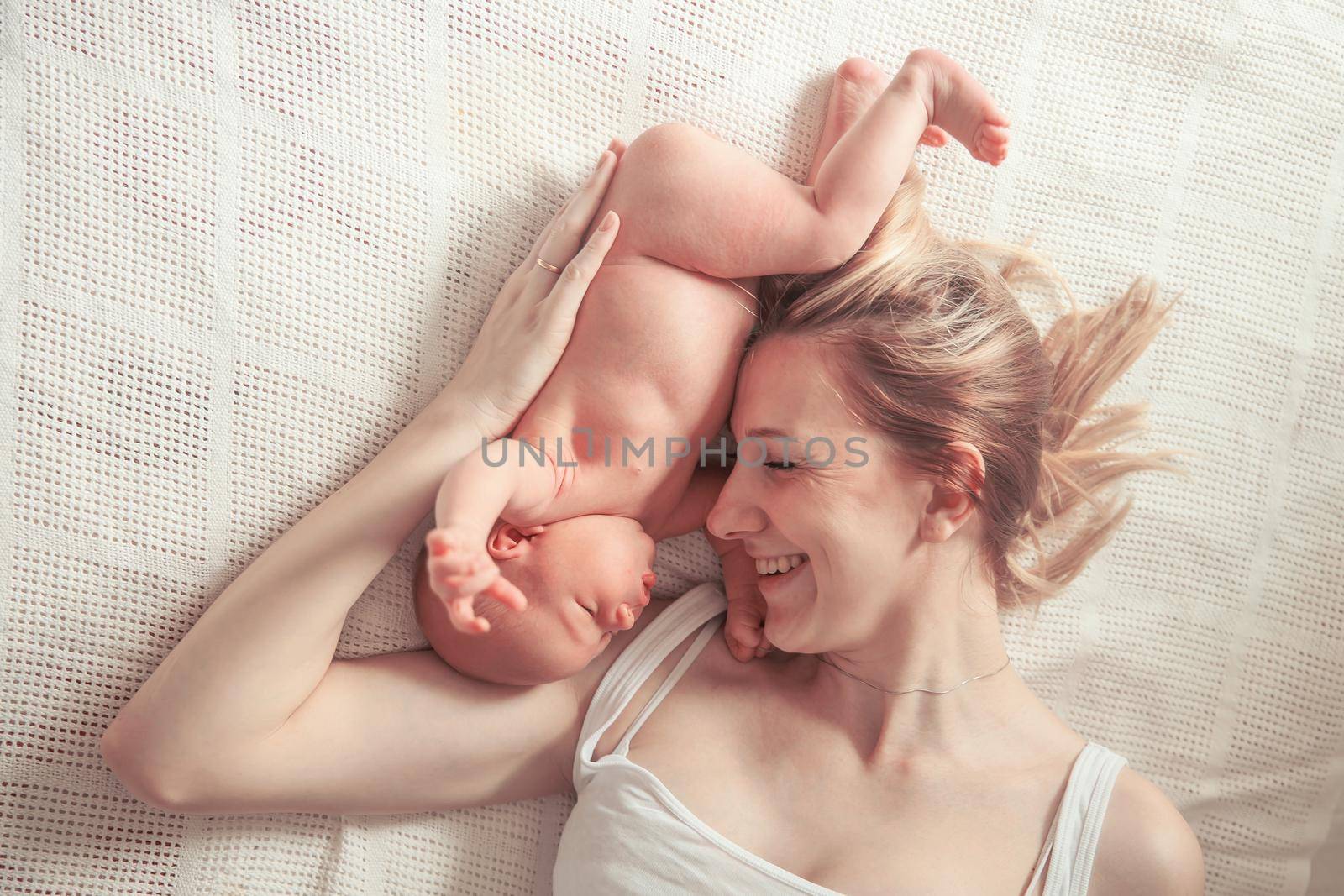 happy motherhood concept - happy mother and newborn baby on a white blanket