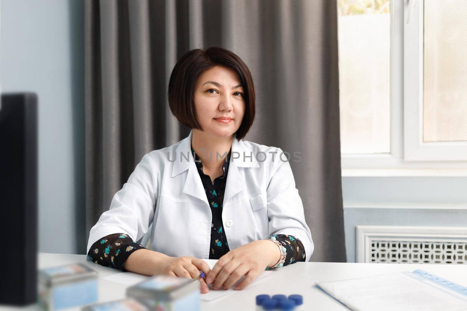 Portrait of a female doctor in an office at a table in a Kazakhstan clinic.