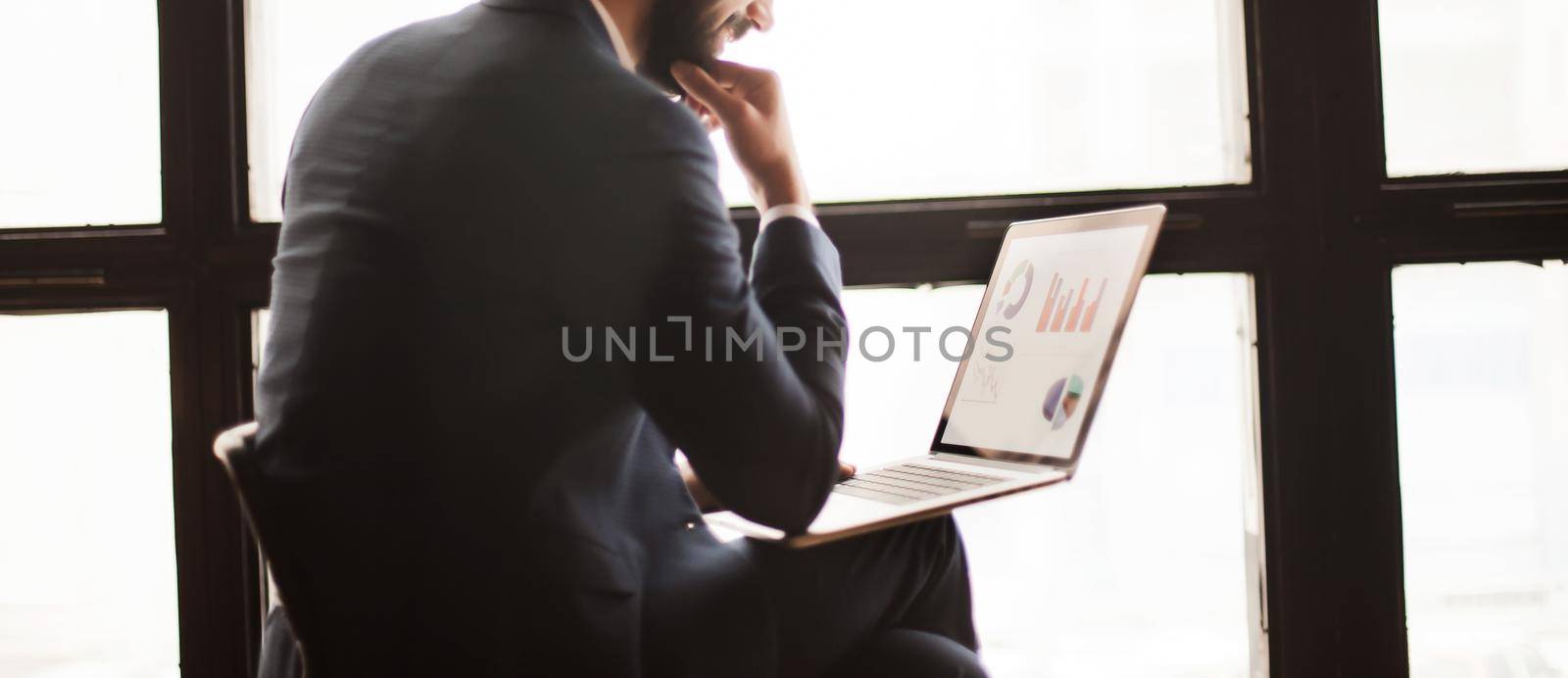 Manager with a laptop, working with financial charts near a larg by SmartPhotoLab