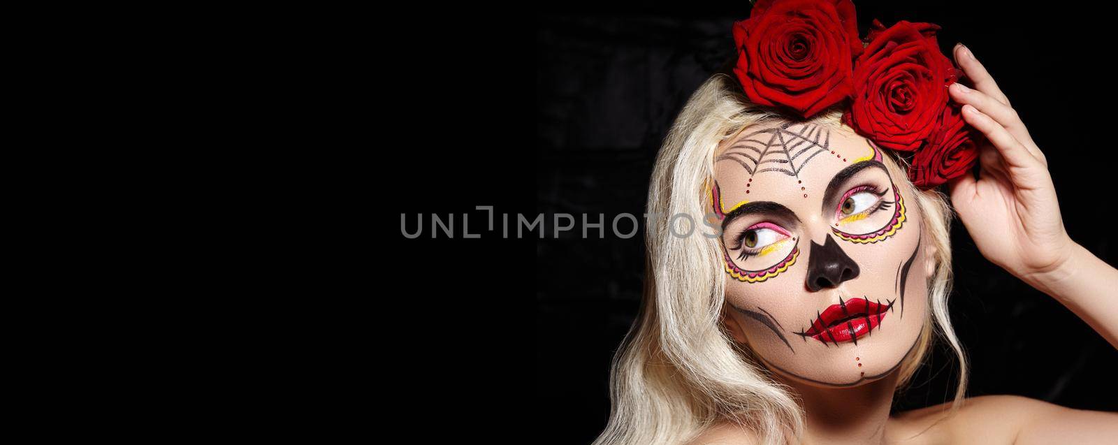 Halloween Make-Up Style. Blond Model Wear Sugar Skull Makeup with Red Roses. Dia de los Muertos or Santa Muerte concept by MarinaFrost