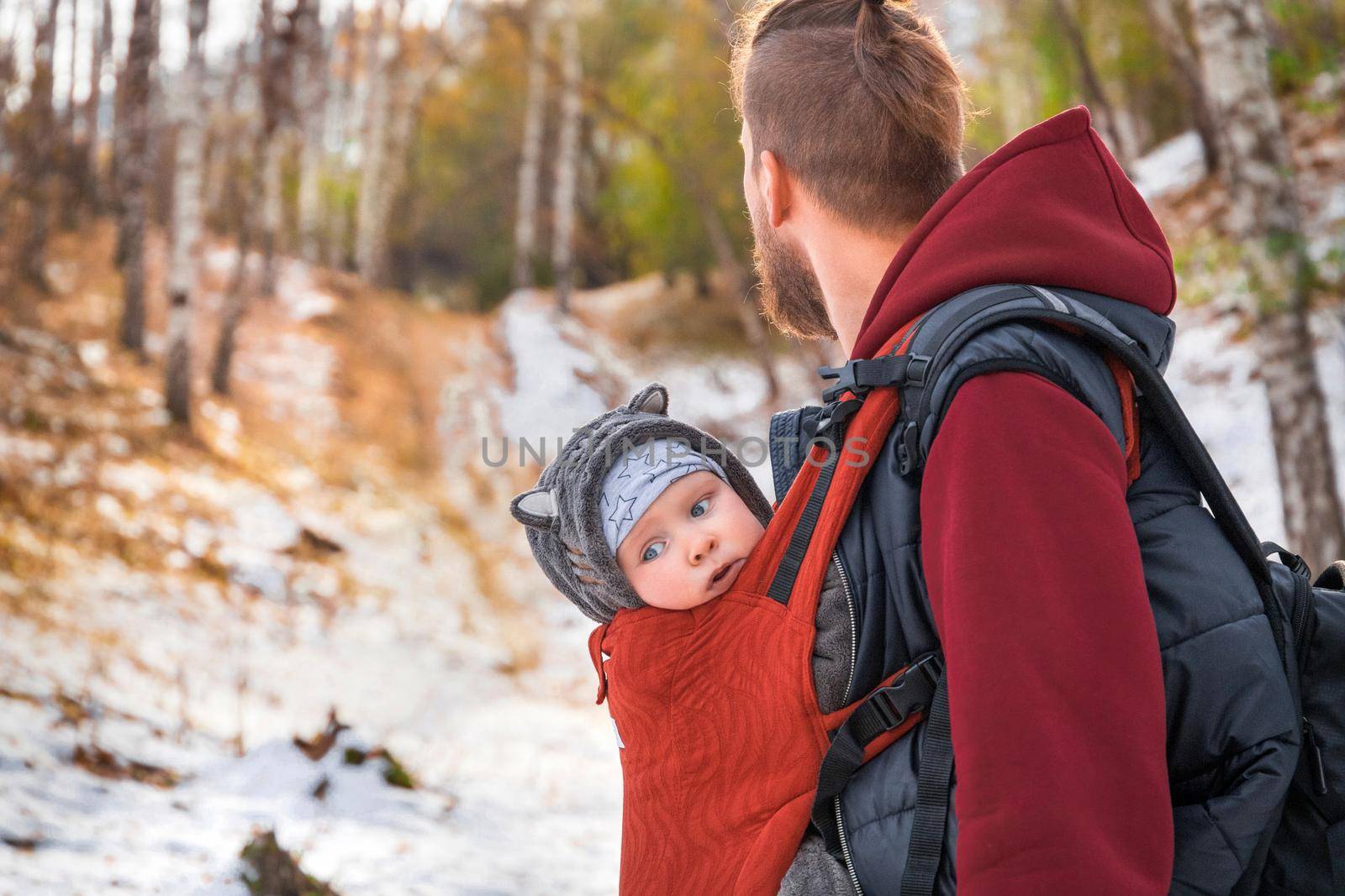 Babywearing autumn walk of a father and his little child in a sling.