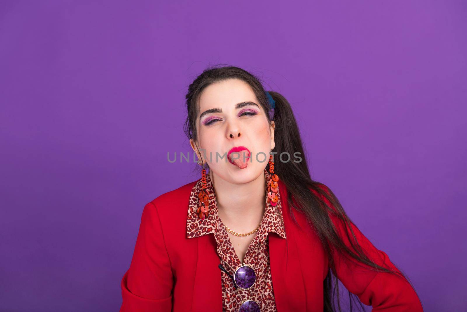 Young woman dressed not fashionably shows tongue at the camera.