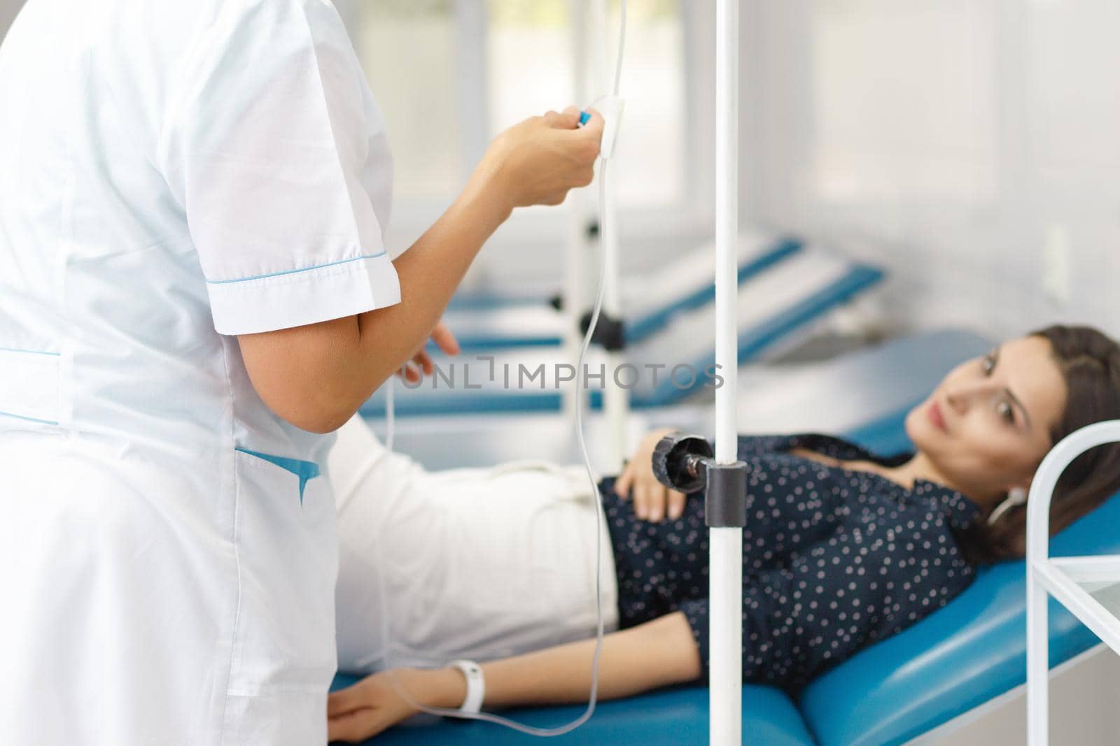 Nurse from Central Asia ready to deliver saline drip to patient on couch.