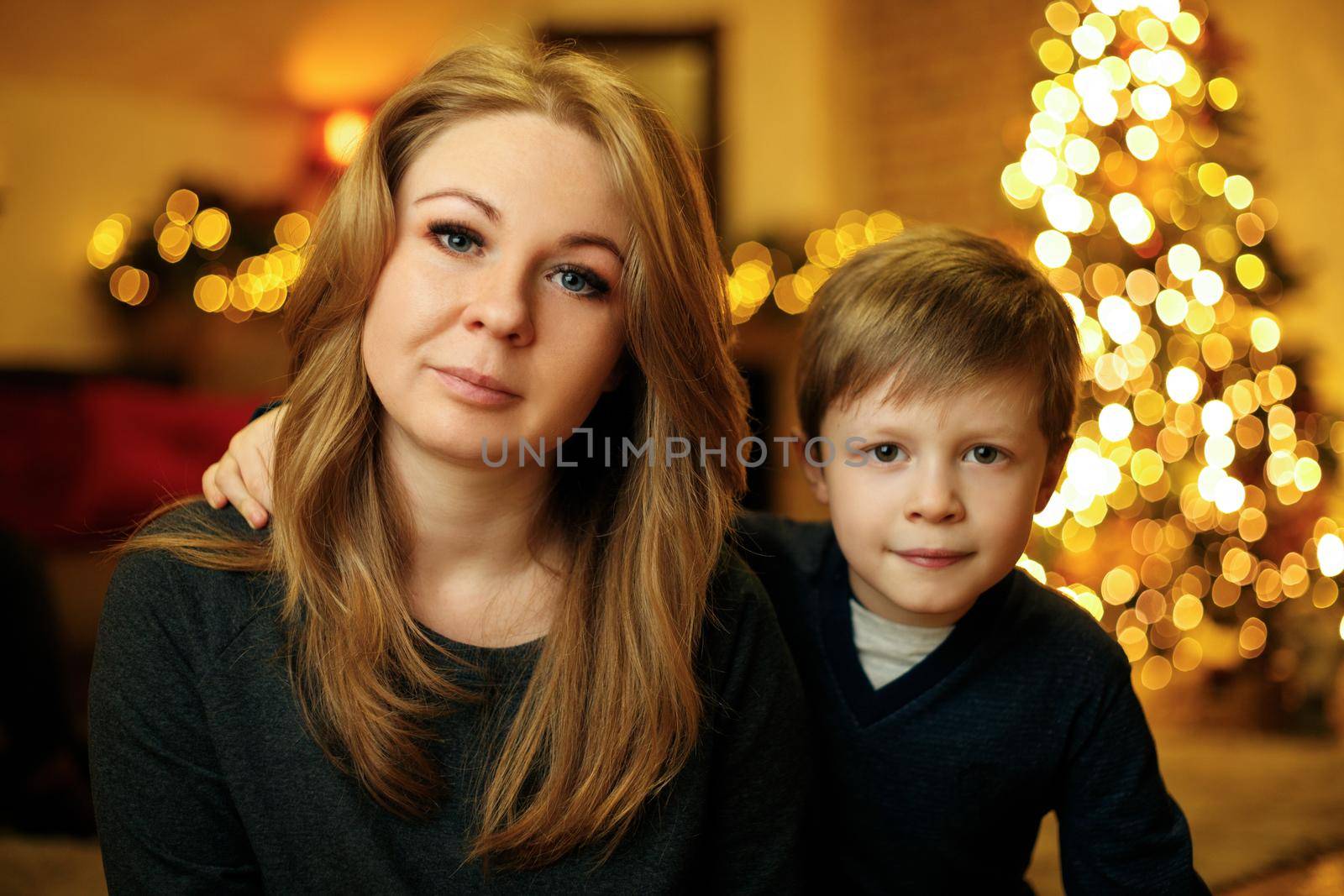 Portrait of a 30 year old beautiful redhead woman with her child in a festive christmas interior with christmas tree. Selective soft focus, film grain effect