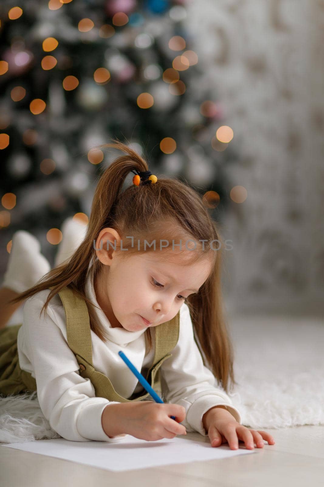 Cute little girl with ponytails is writing a letter to santa claus, vertical copy space.