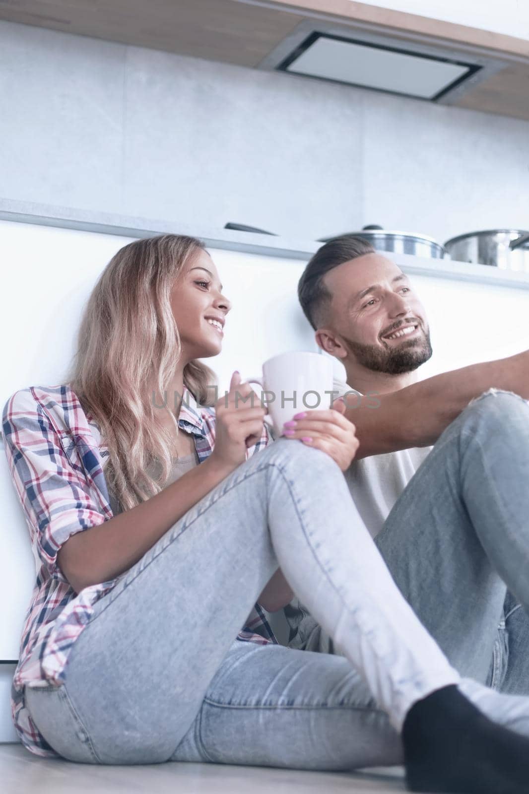 young couple drinking coffee sitting on the kitchen floor by asdf