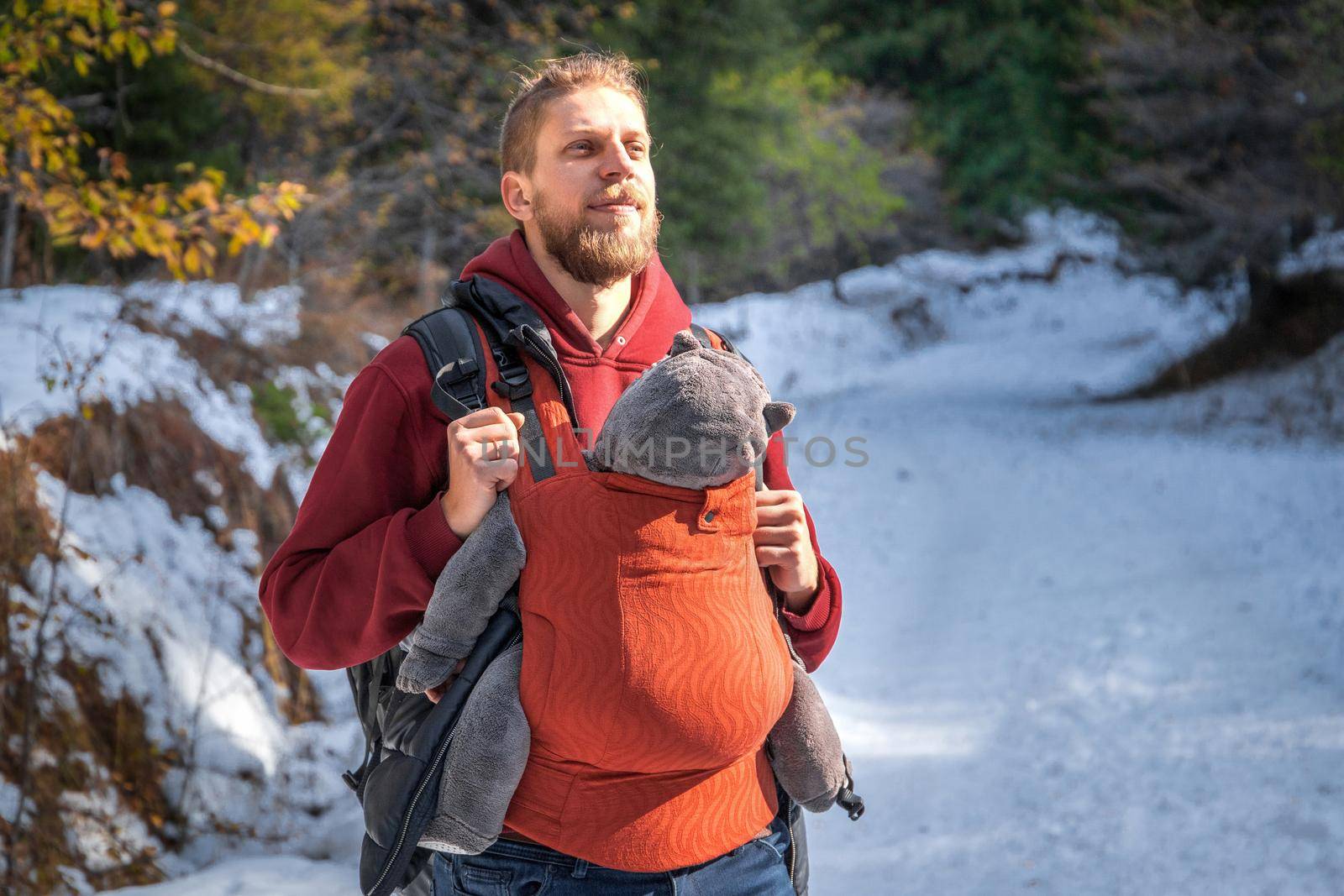 Young father with his baby boy in ergonomic baby carrier in winter forest.