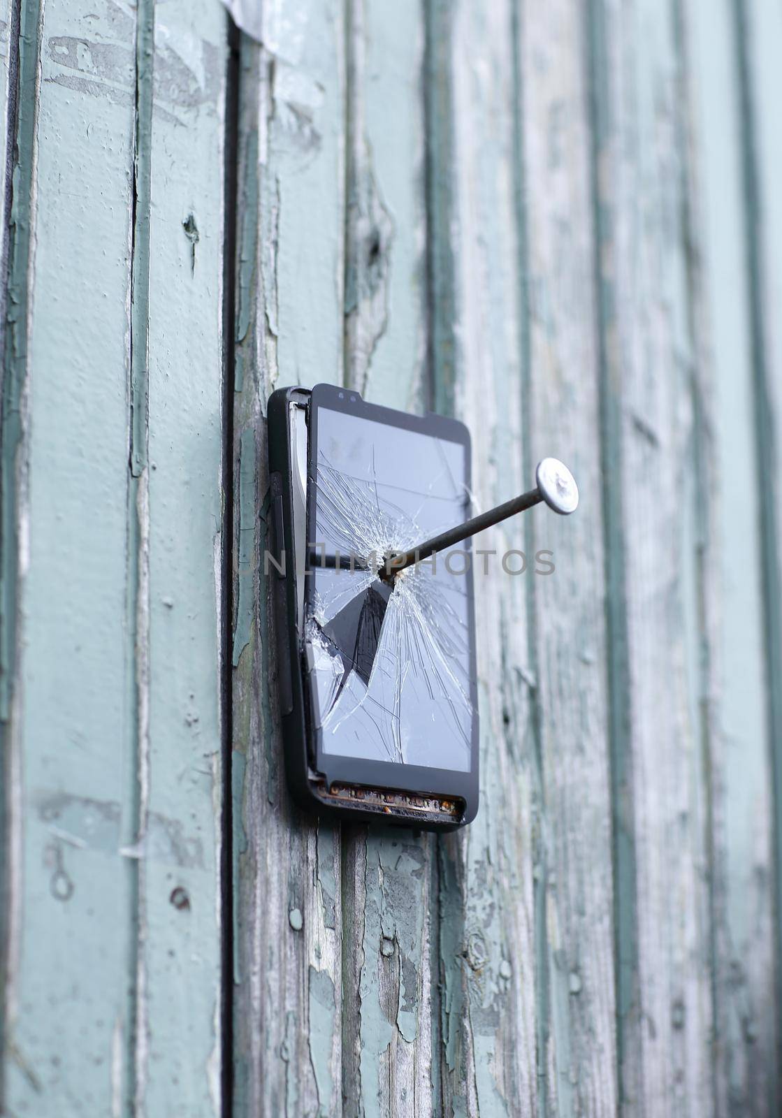 faulty mobile phone is nailed to an old fence.the concept of obsolete technology