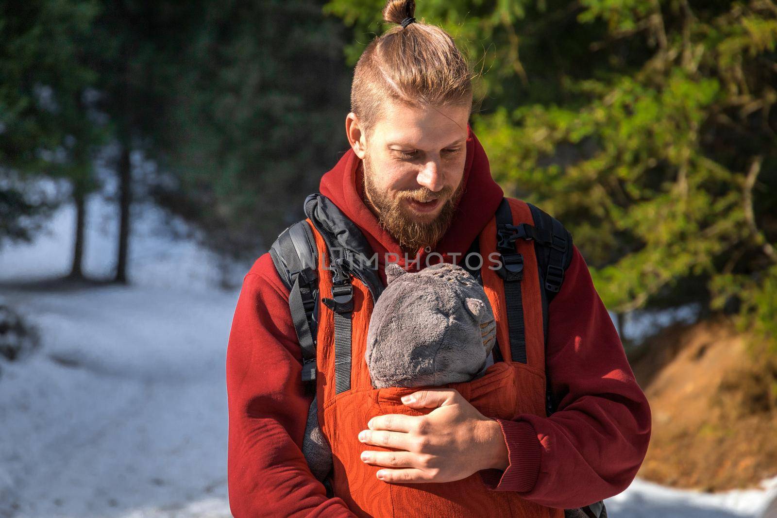 Young bearded father with his baby boy in ergonomic baby carrier in winter outdoor.