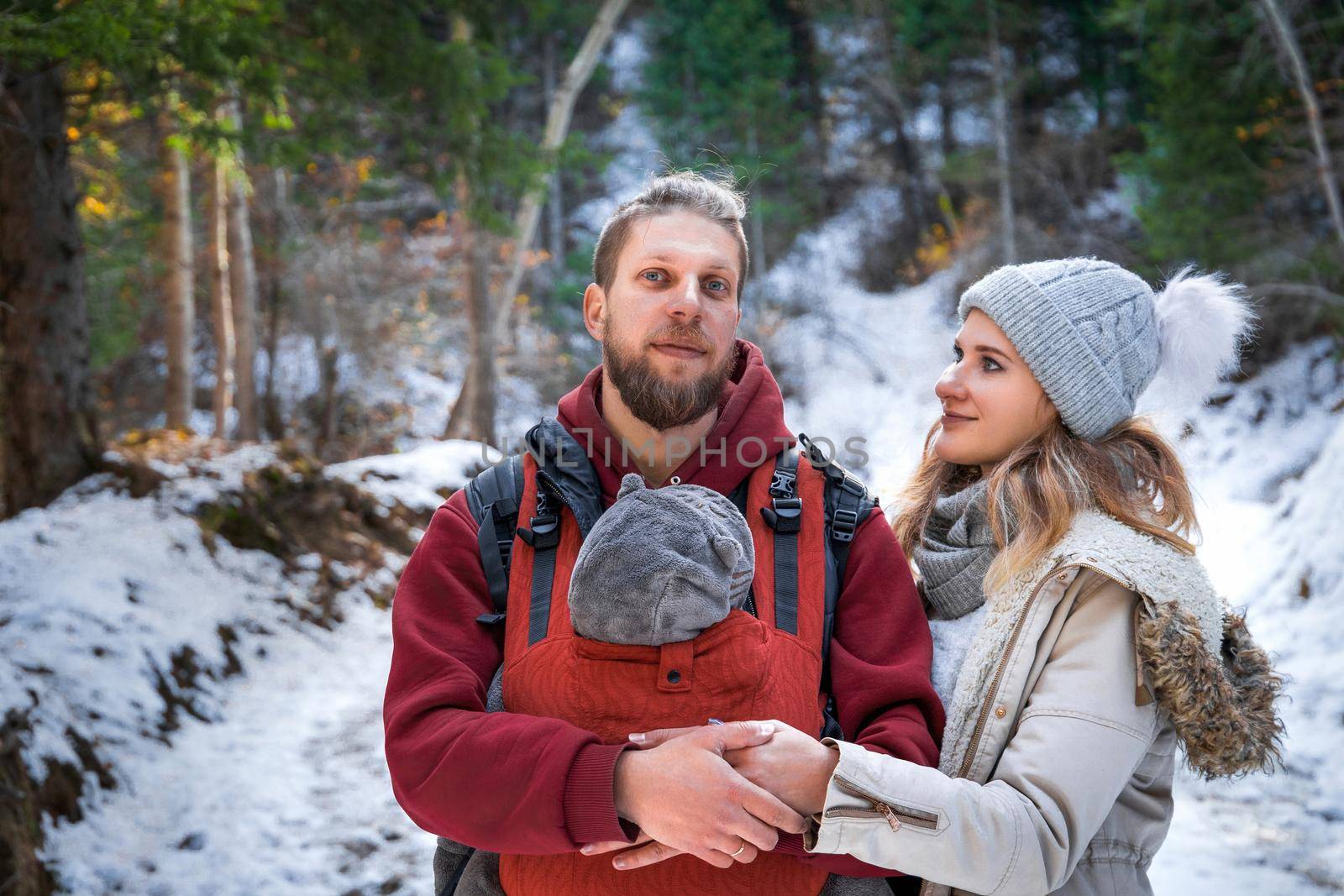 Portrait of young babywearing family with his son in baby sling, winter weekend outdoor.