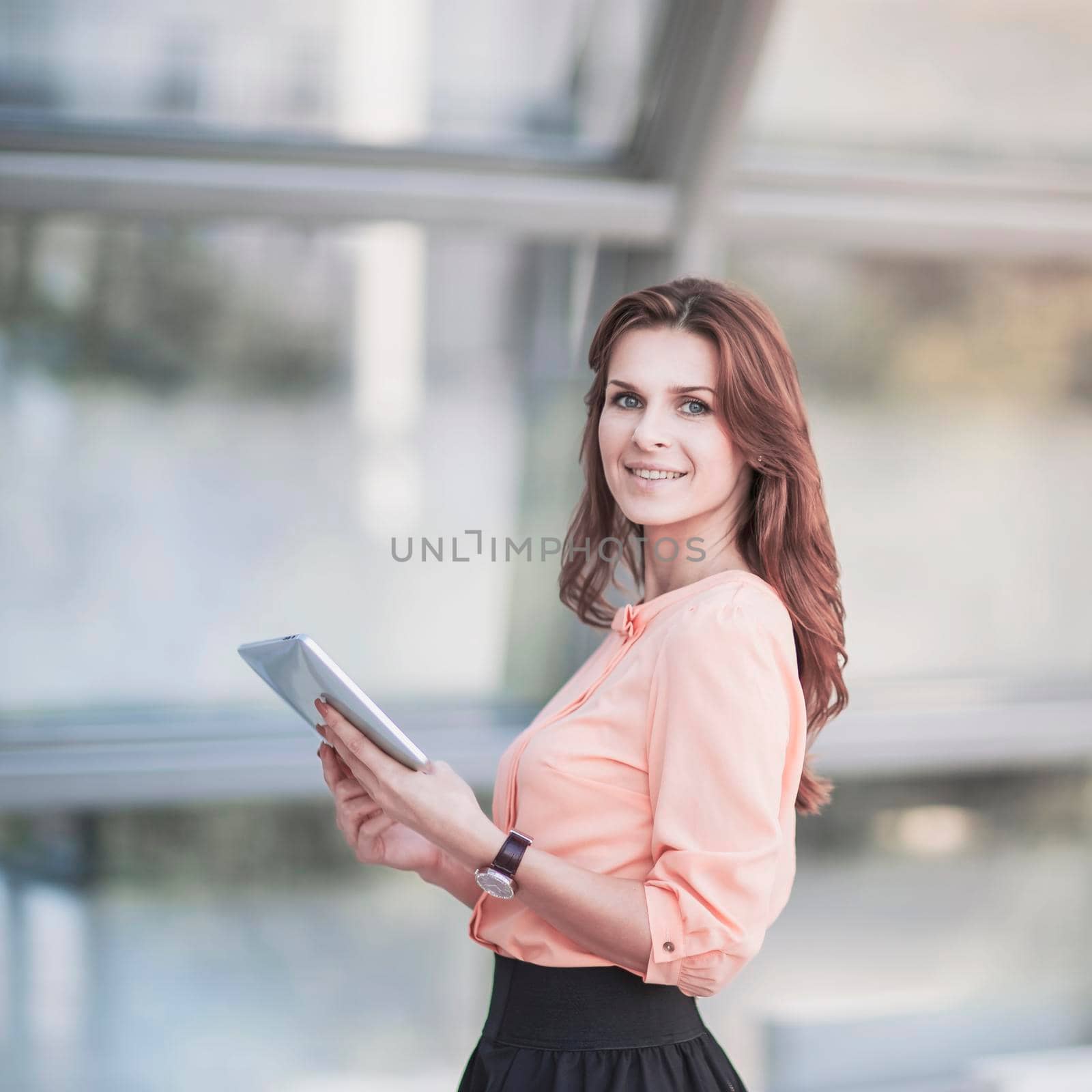 successful business woman with digital tablet standing in the lobby of a modern office by SmartPhotoLab