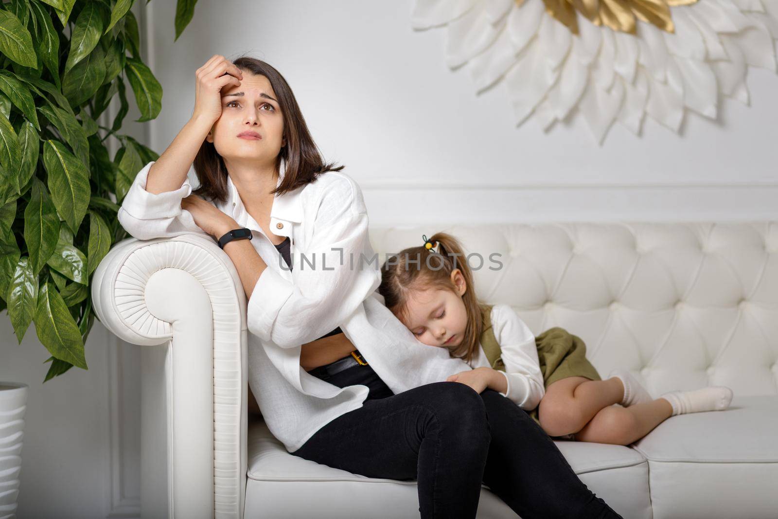 Tired mother suffering from experiencing depression and her sleeping kid. Motherhood mental health care.