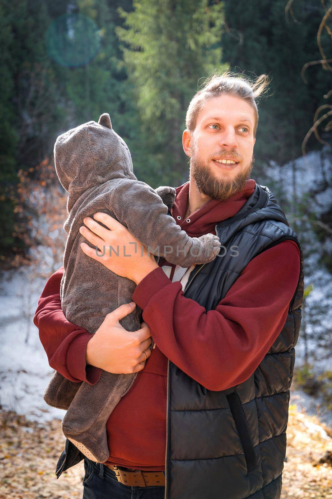Portrait of adorable bearded father with his son in a funny jumpsuit with ears winter outdoor.