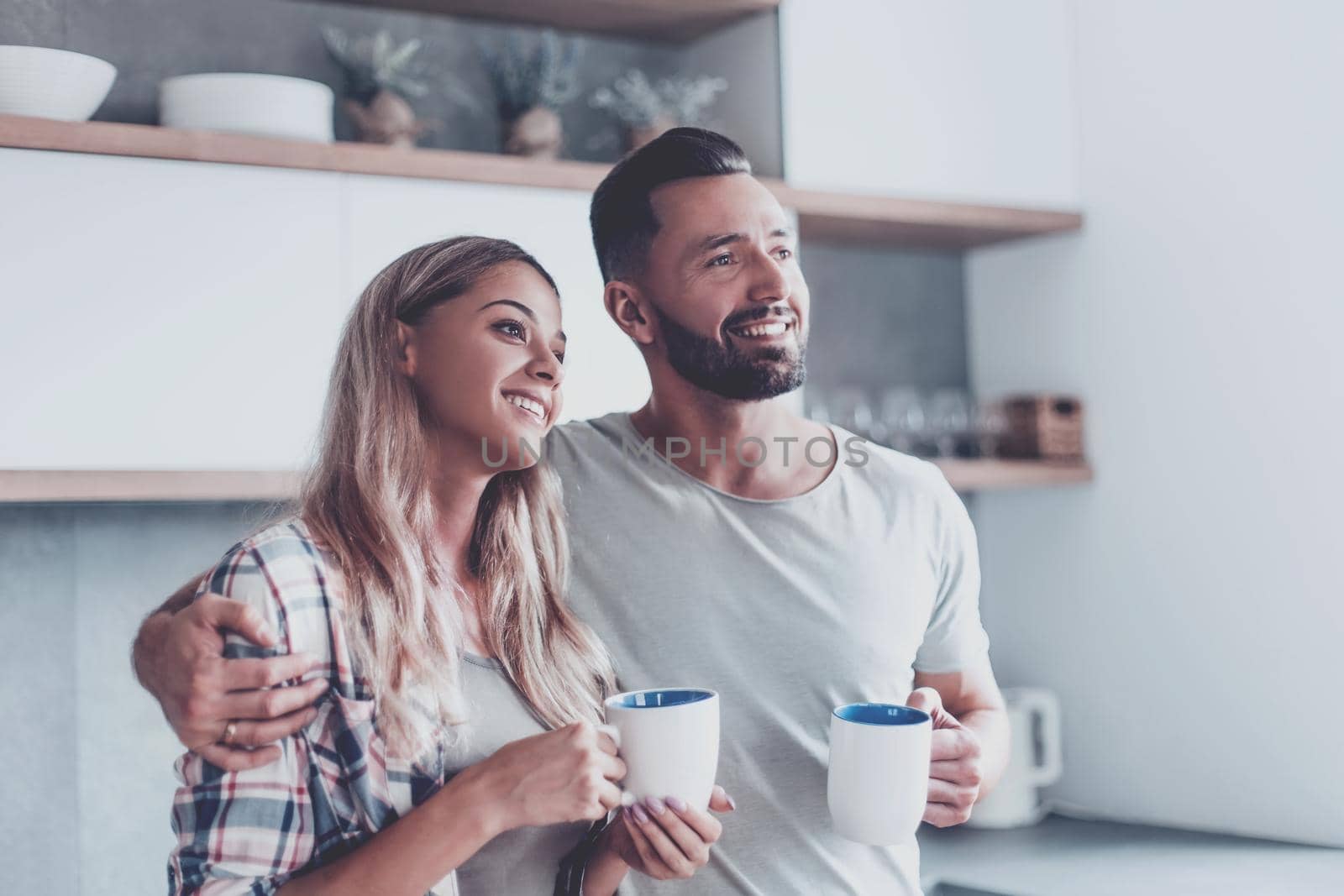 young couple drinking coffee standing in the kitchen by asdf