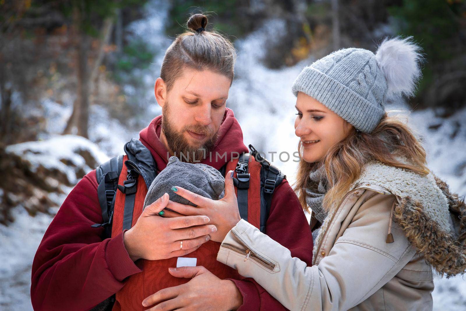 Portrait of young babywearing family with his son in baby sling, winter adventure outdoor.