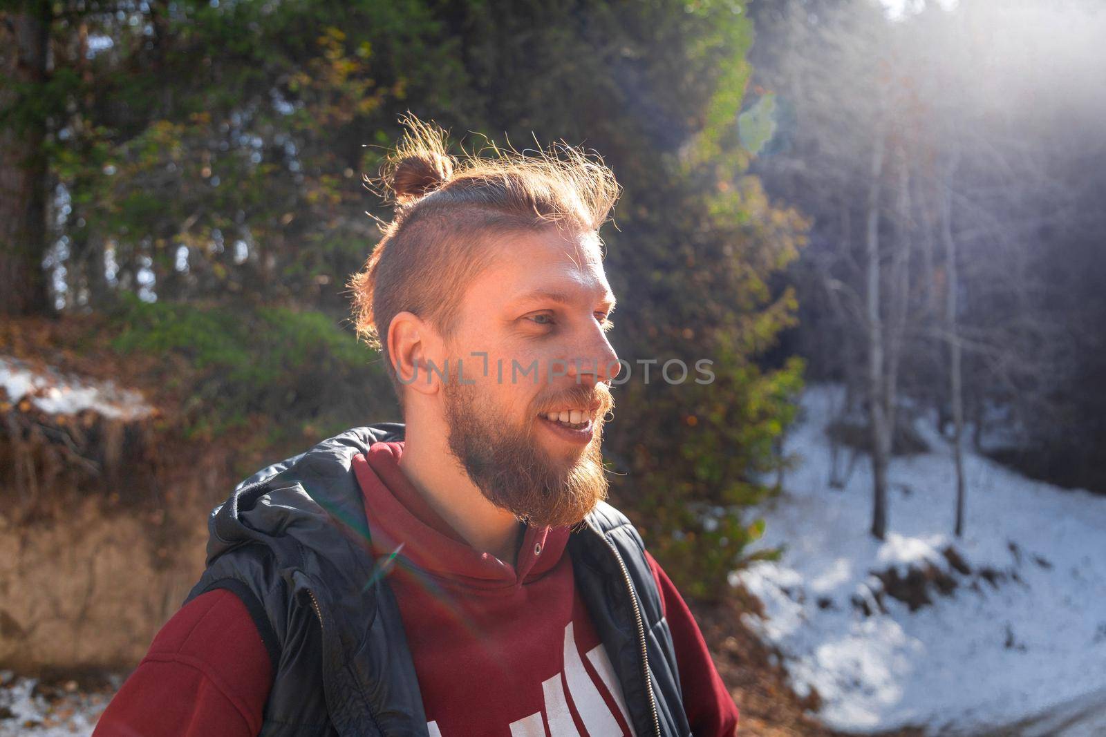 Outdoor portrait of blond bearded smiling hipster man in nature.