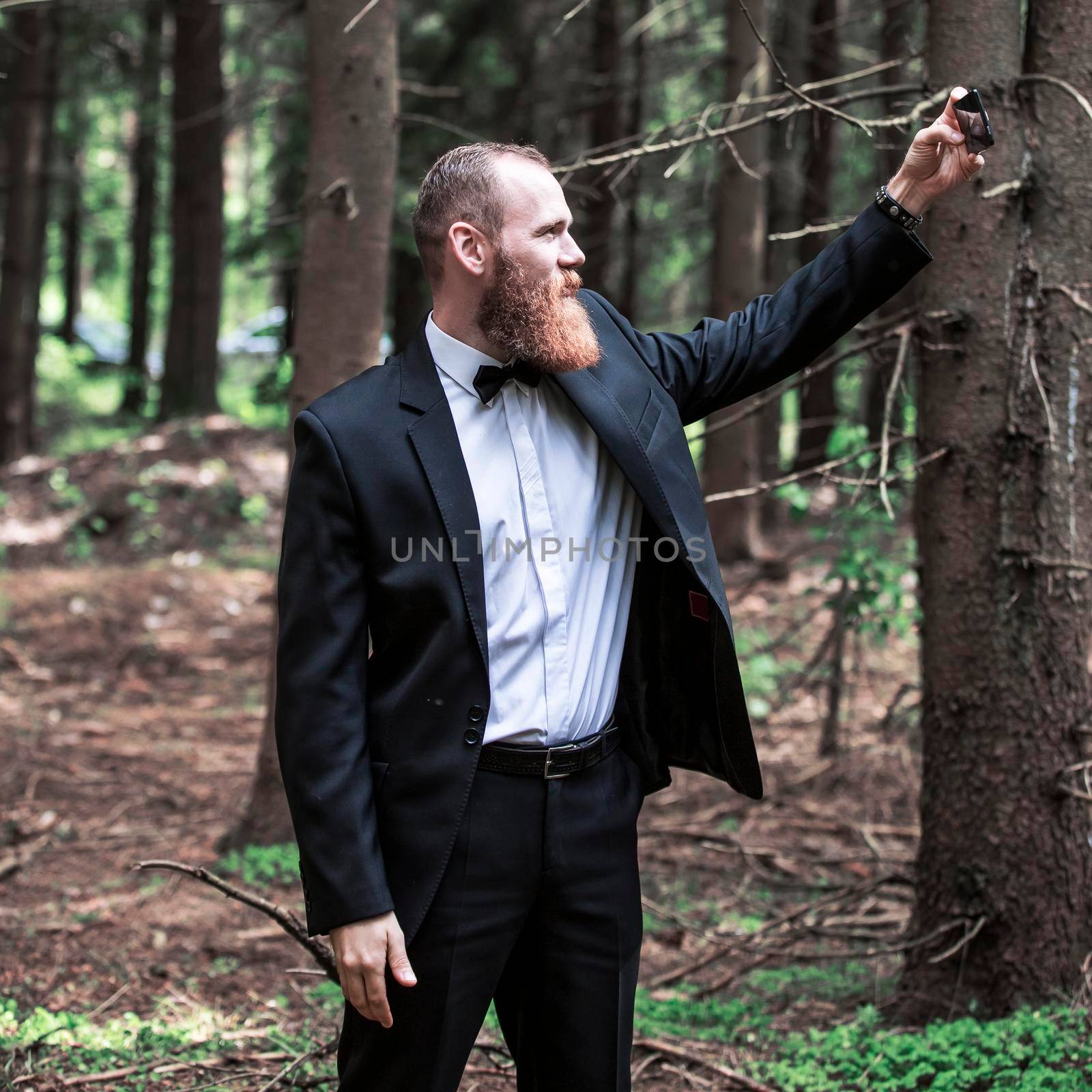 serious man in a business suit taking a selfie in a forest. people and technology