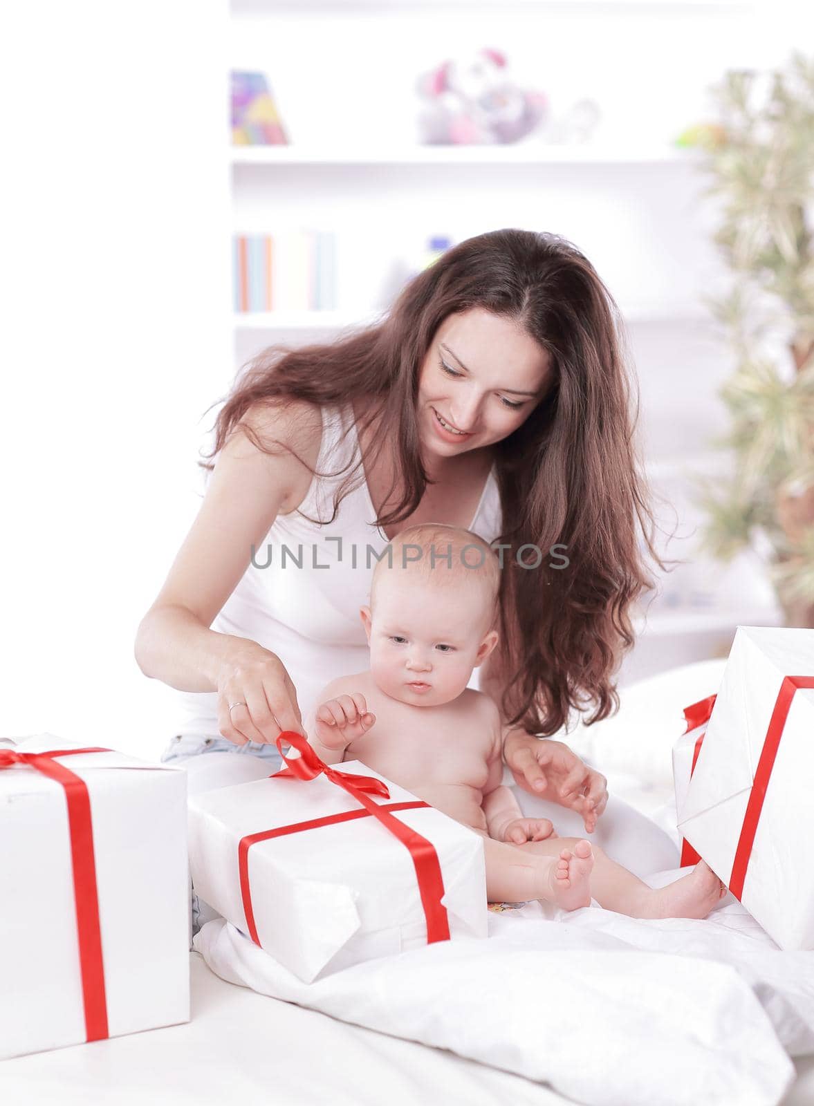 young mother unties the ribbon on the gift boxes by SmartPhotoLab