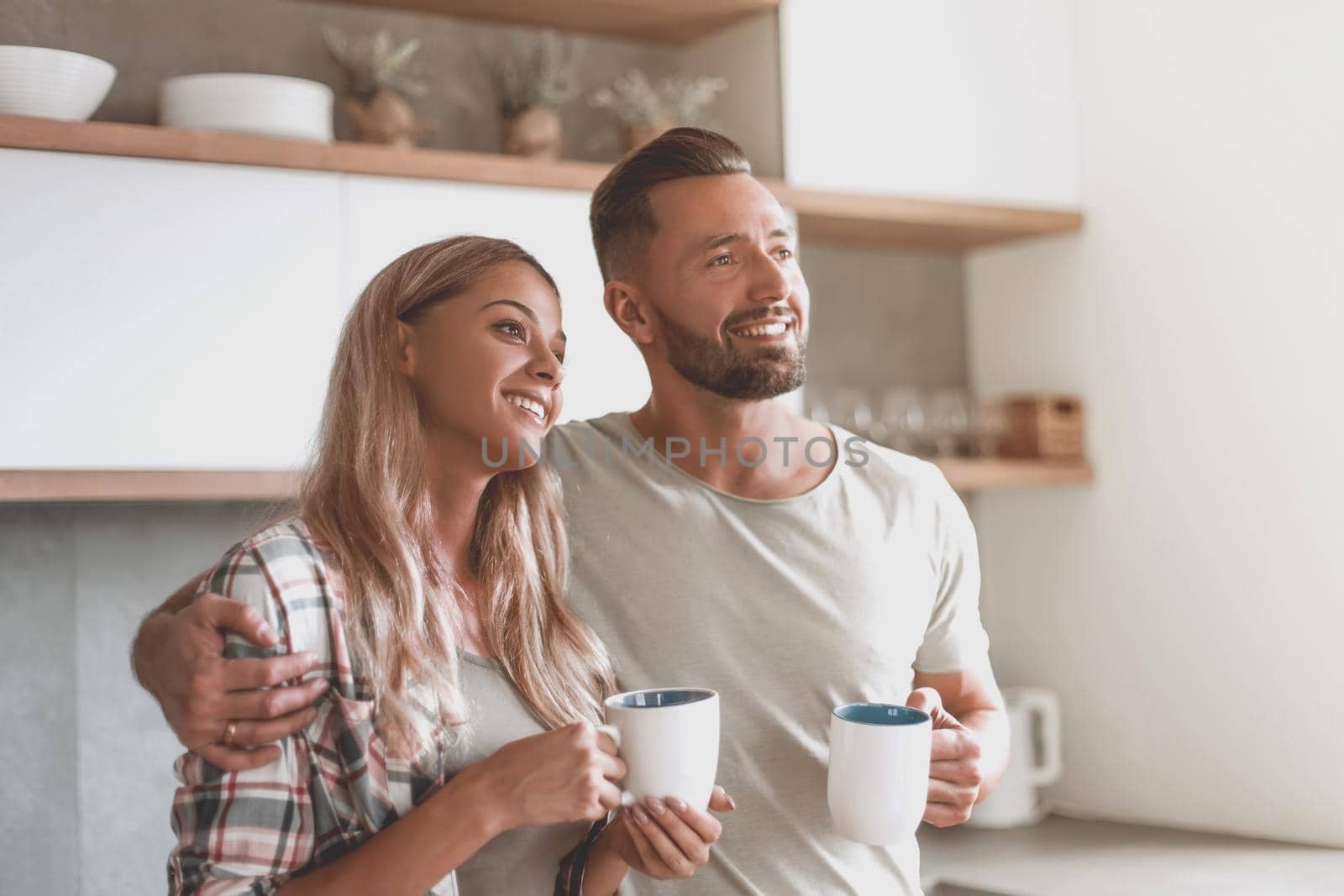 young couple drinking coffee standing in the kitchen by asdf
