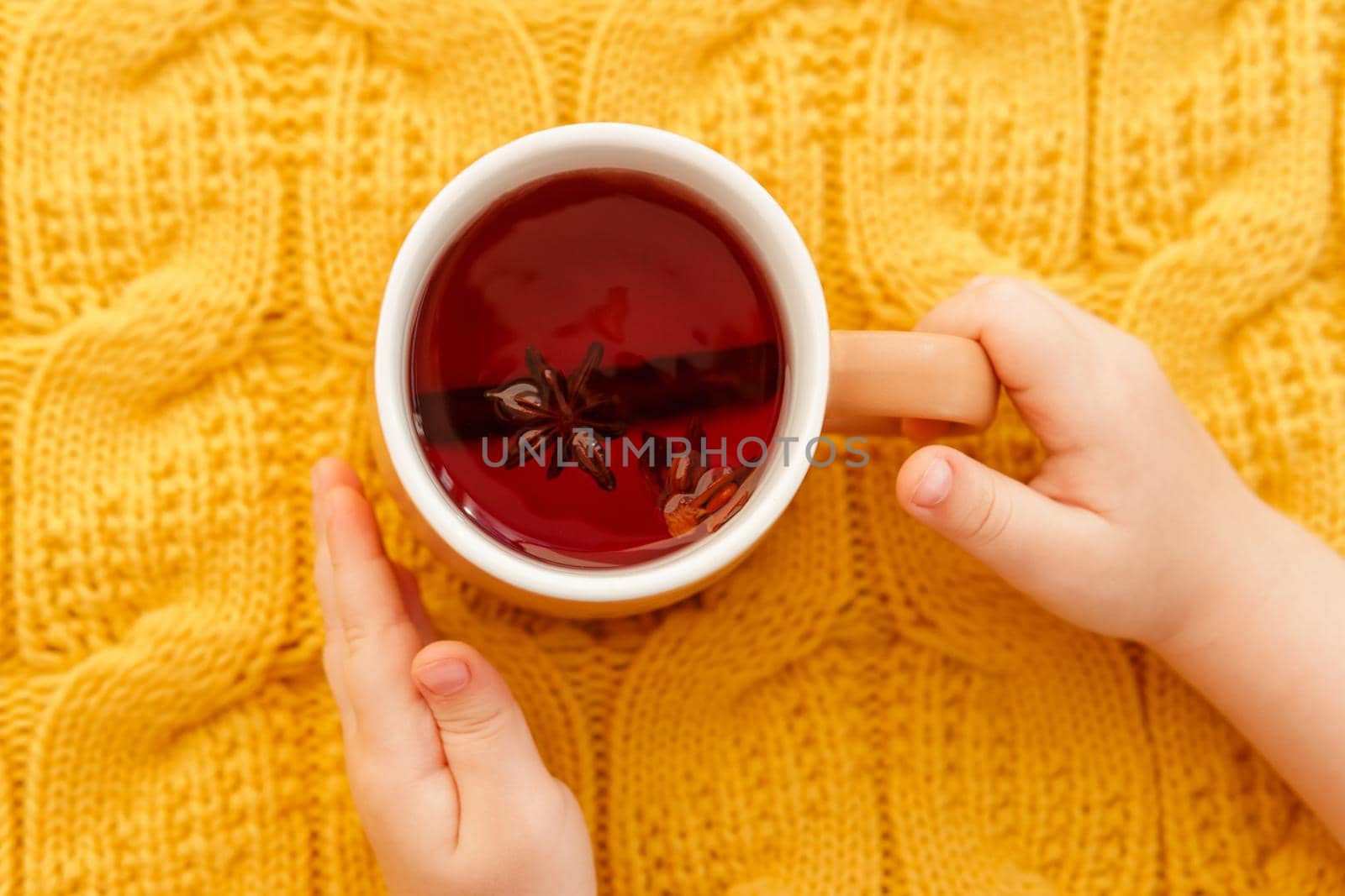 Karkade tea in an orange cup on an orange knitted background. The concept of the autumn season, natural colors. Red fruit tea.